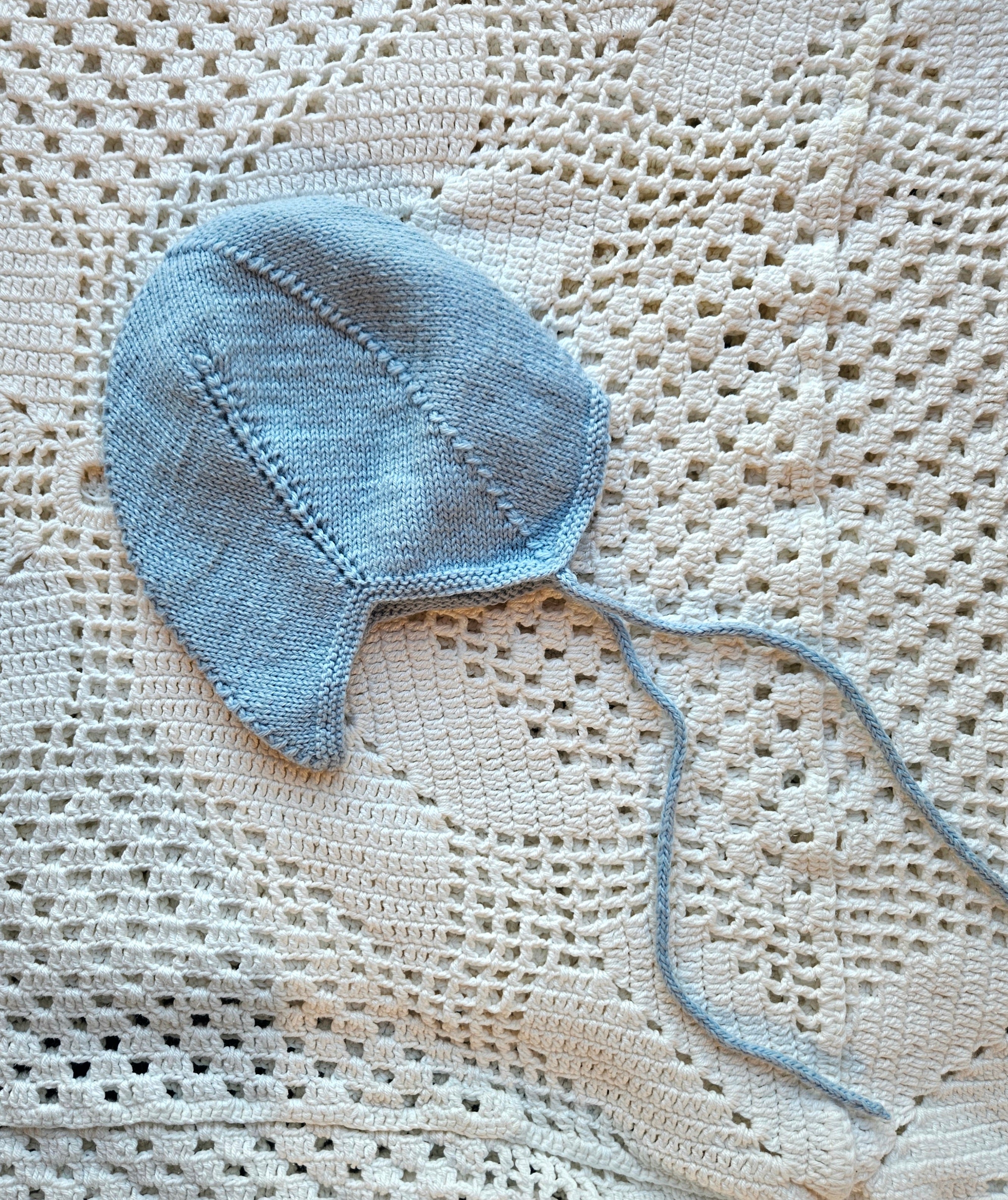 Blue knitted baby hat on a textured beige surface