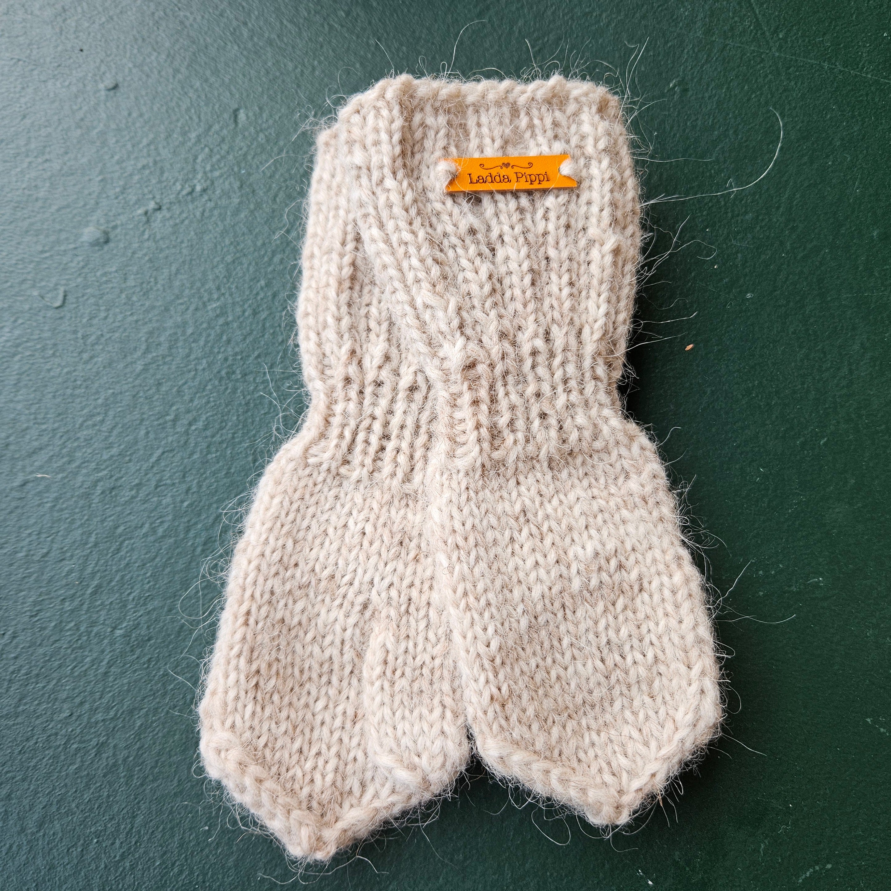 Knitted mittens with a label on a dark surface