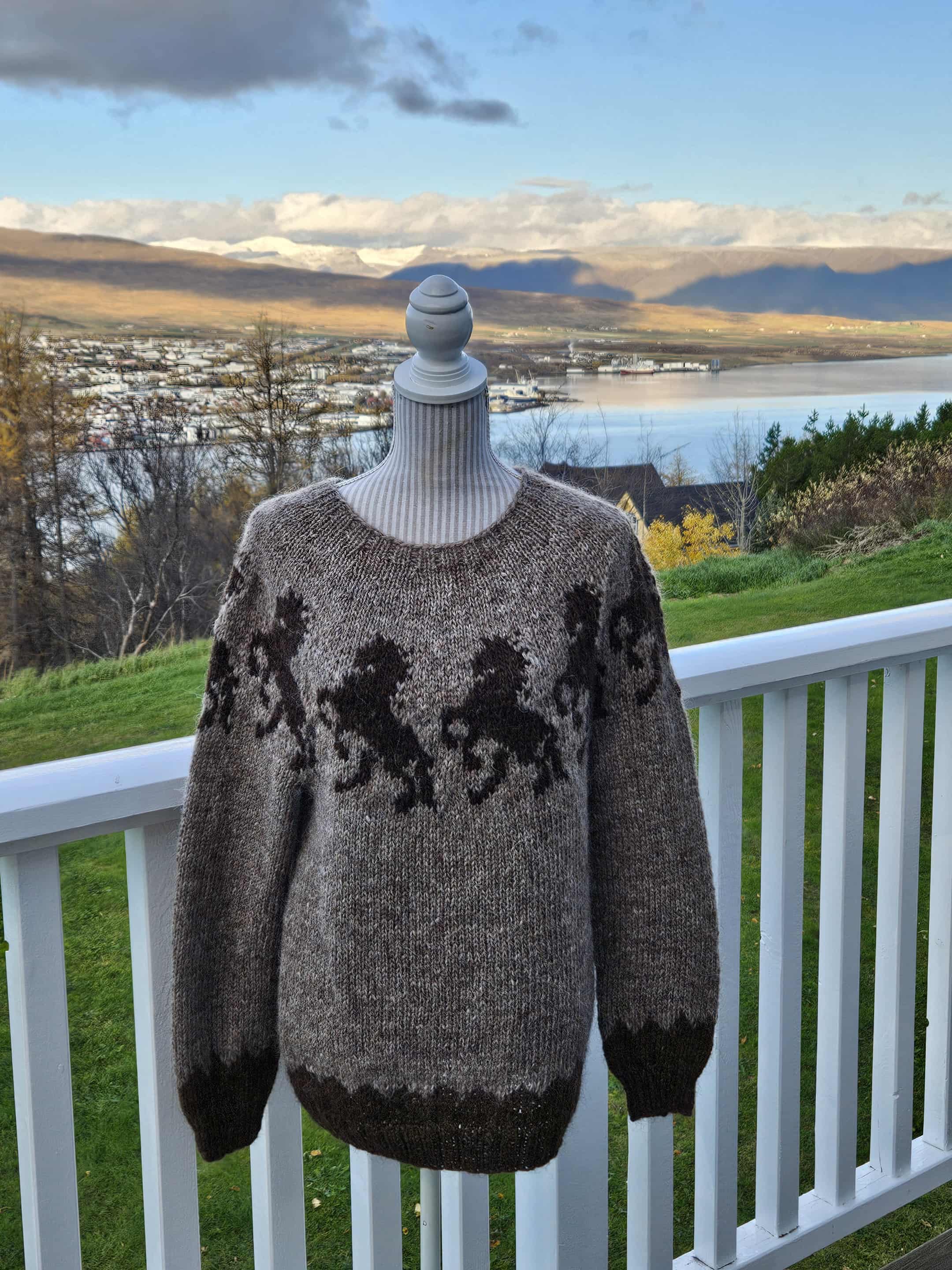 Sweater with horse design on a mannequin against a scenic background