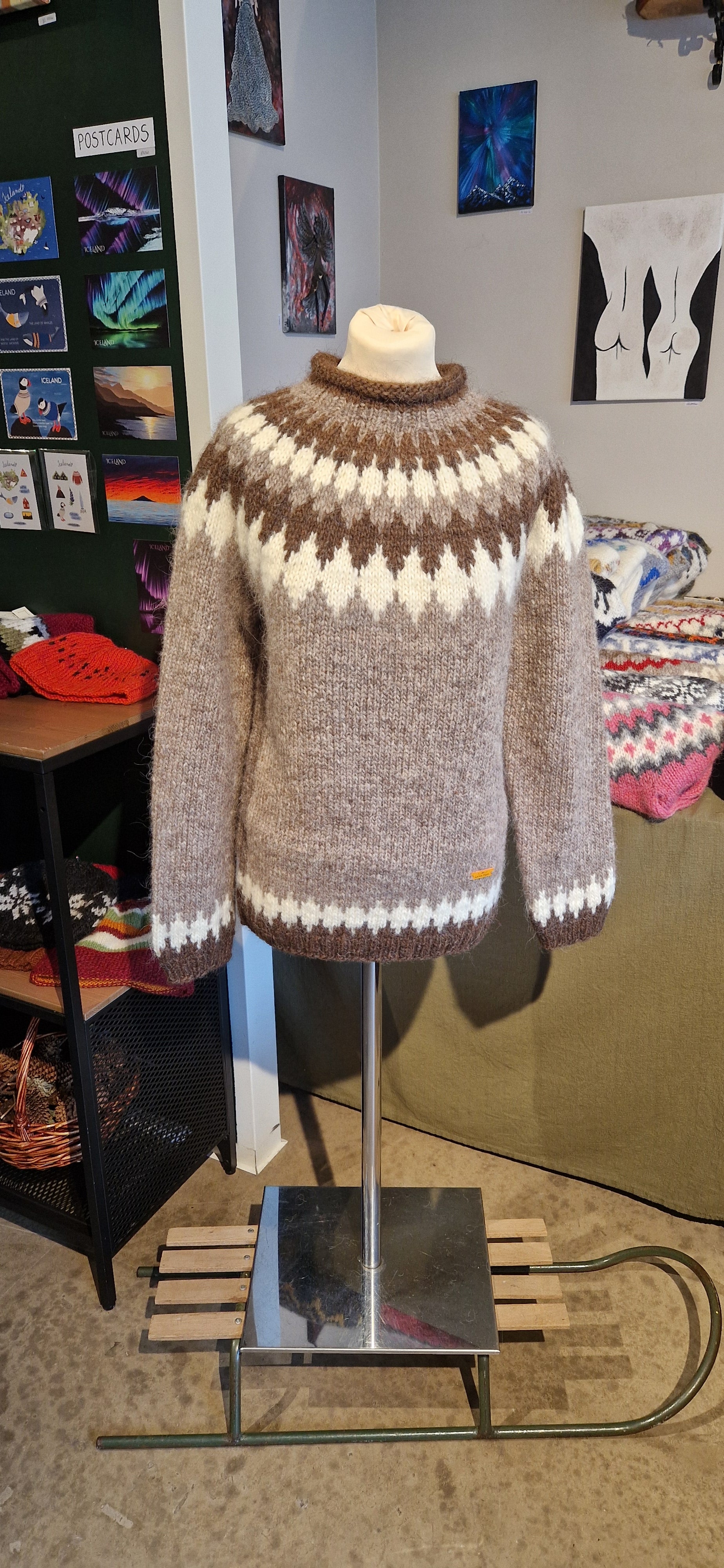 Brown and white striped sweater on a mannequin against a wall with various items and decorations.