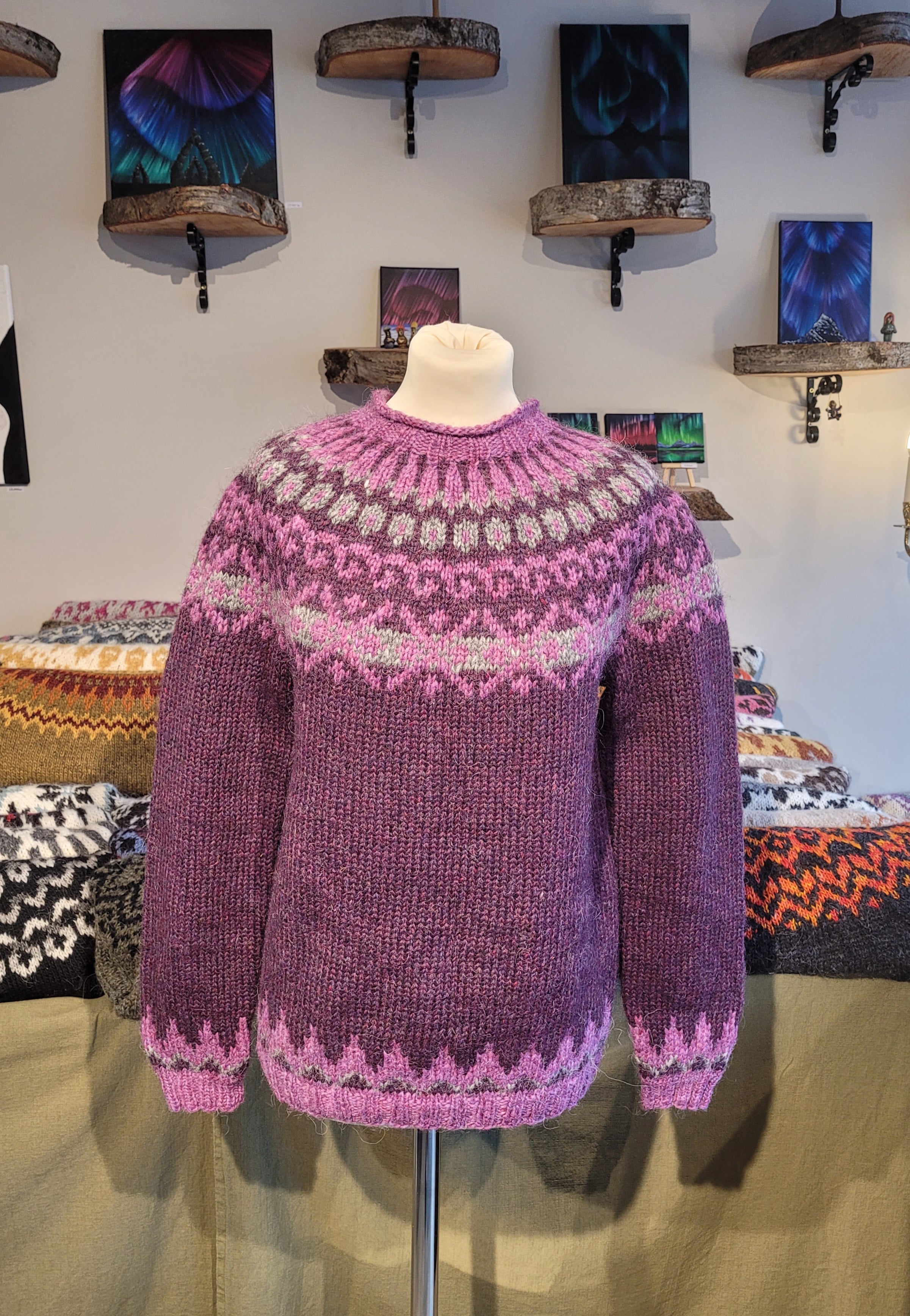 A mannequin in a purple hand-knit Icelandic wool sweater featuring a traditional Nordic pattern in light purple in a store setting.