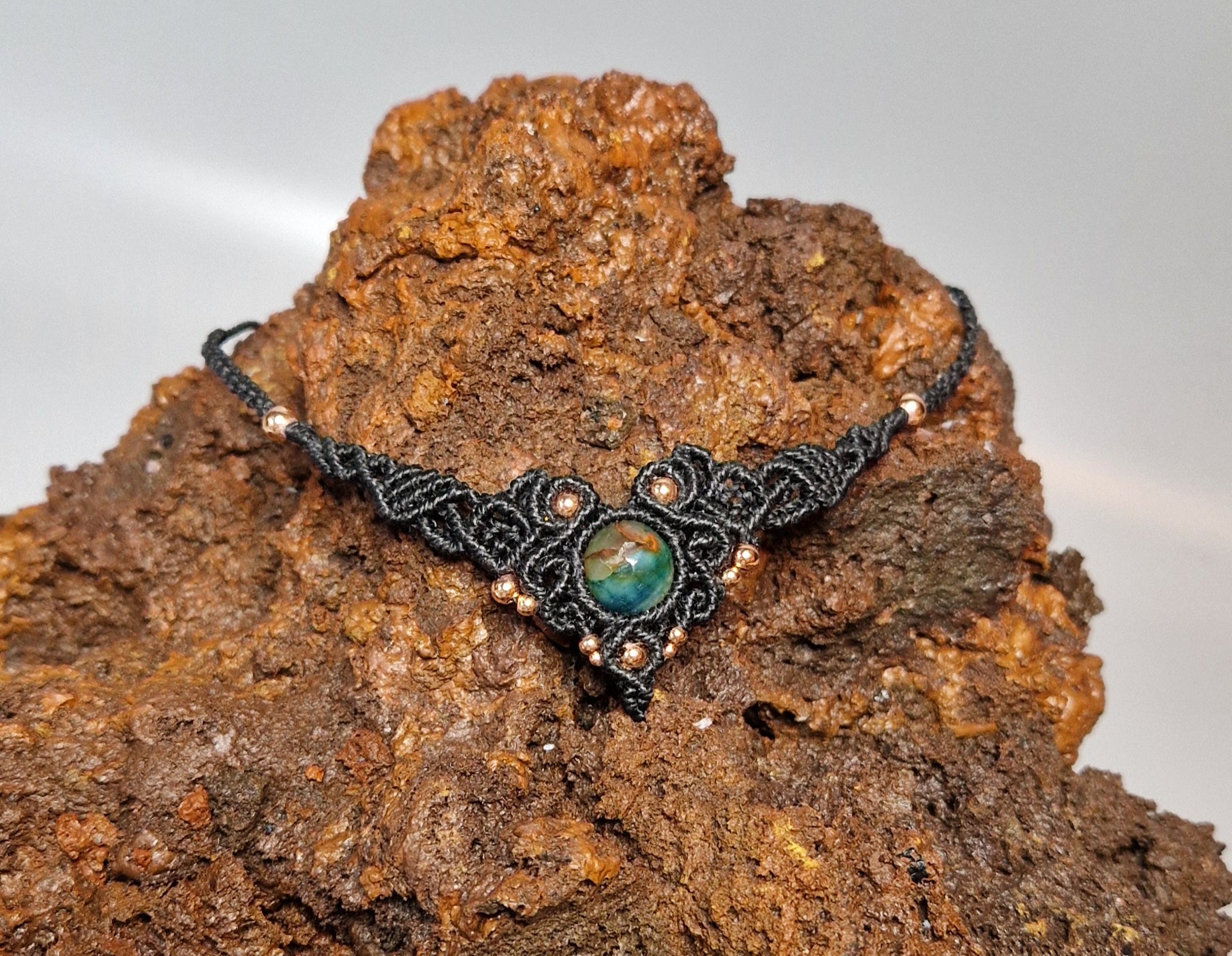 Necklace with a green gemstone on a textured brown surface