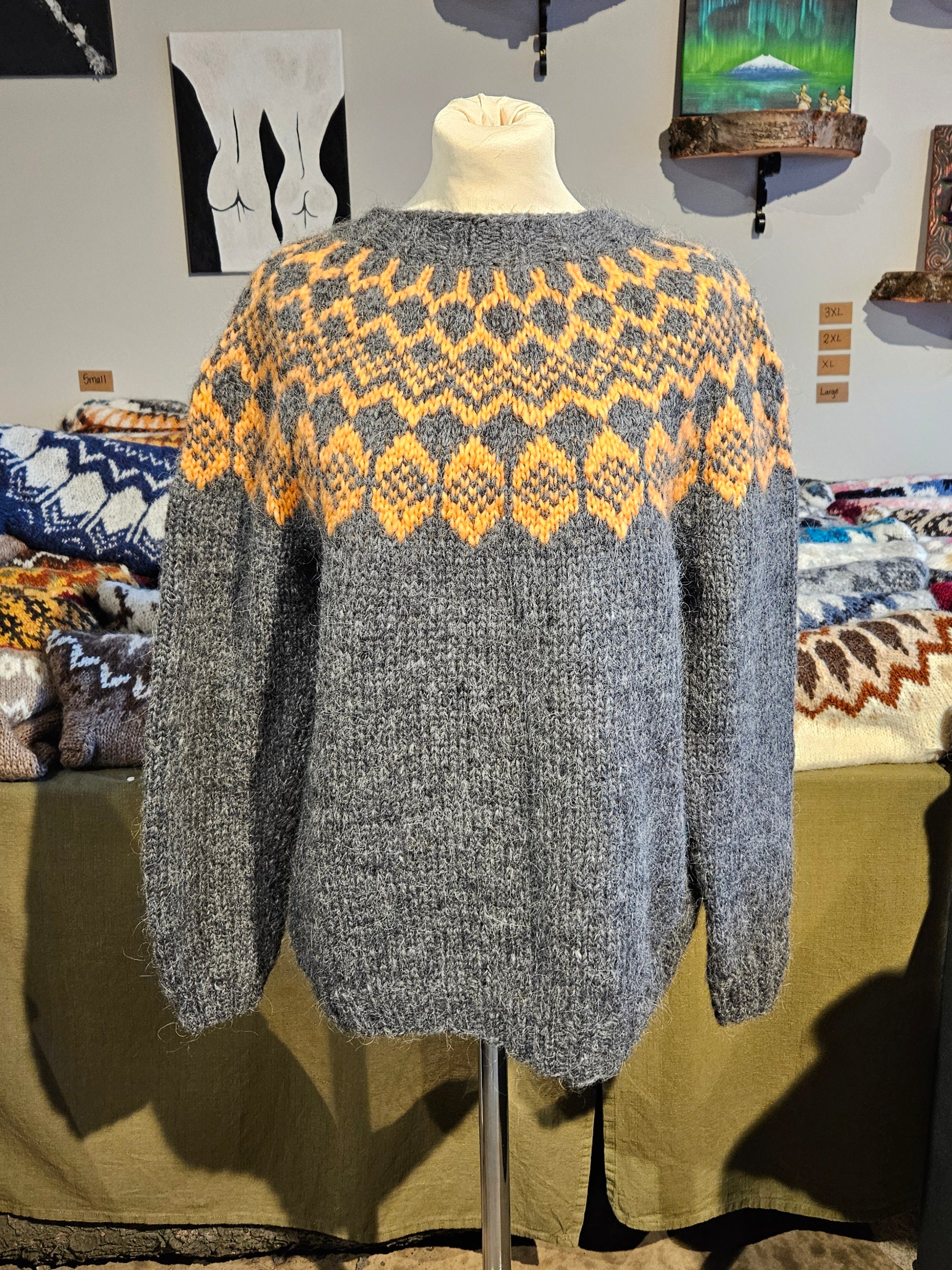 Gray sweater with yellow pattern on a mannequin in a store setting.