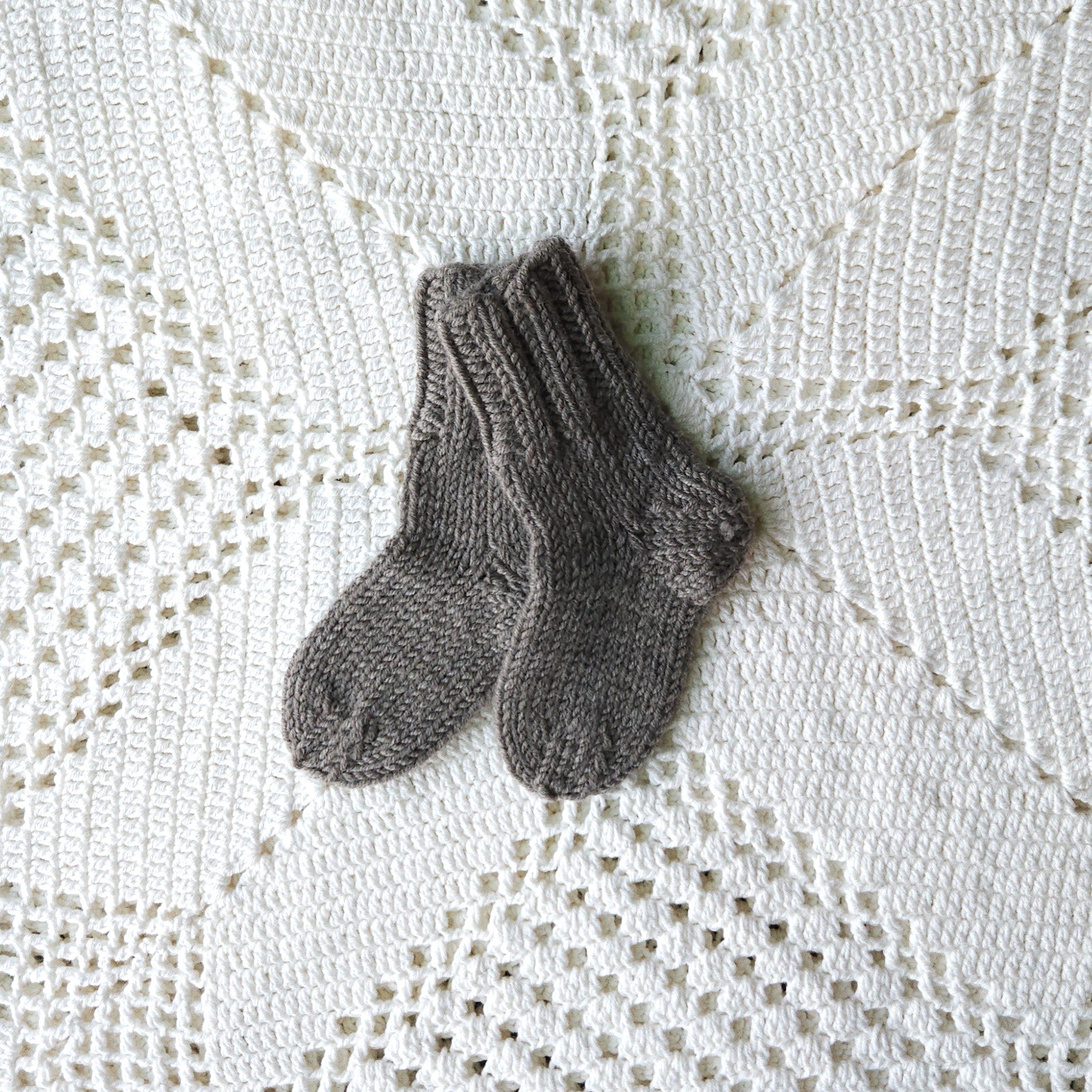 Pair of gray knitted socks on a textured white surface