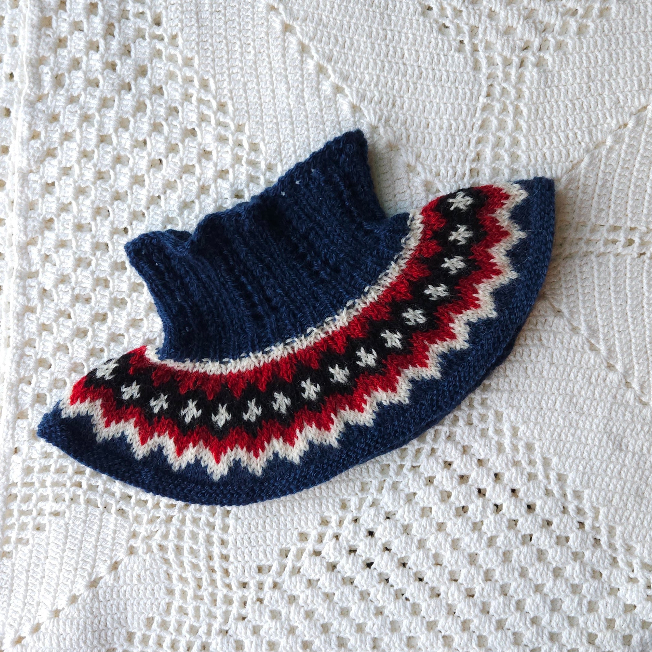 Knitted neck warmer with a colorful pattern on a white lace background