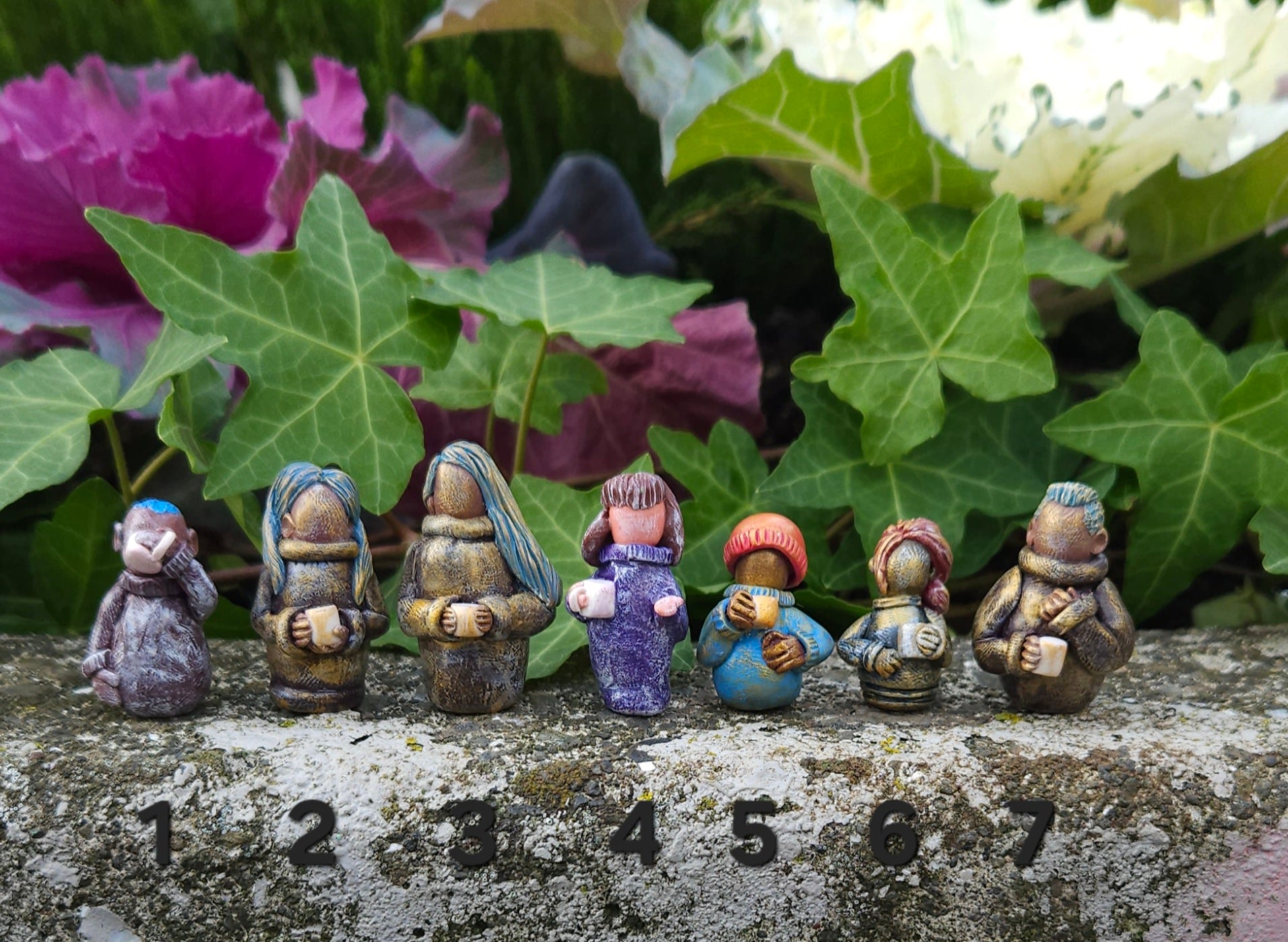 Small figurines of people on a stone surface with plants in the background