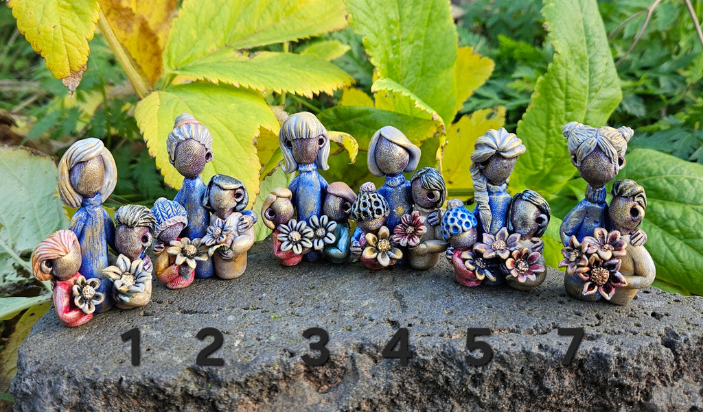 Set of small ceramic figurines on a stone surface with green leaves in the background