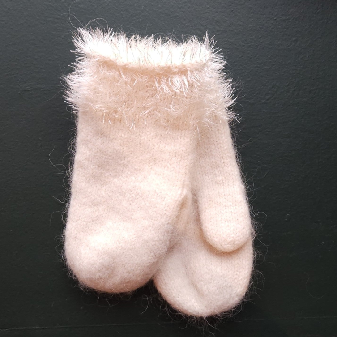 White fluffy mitten on a green background