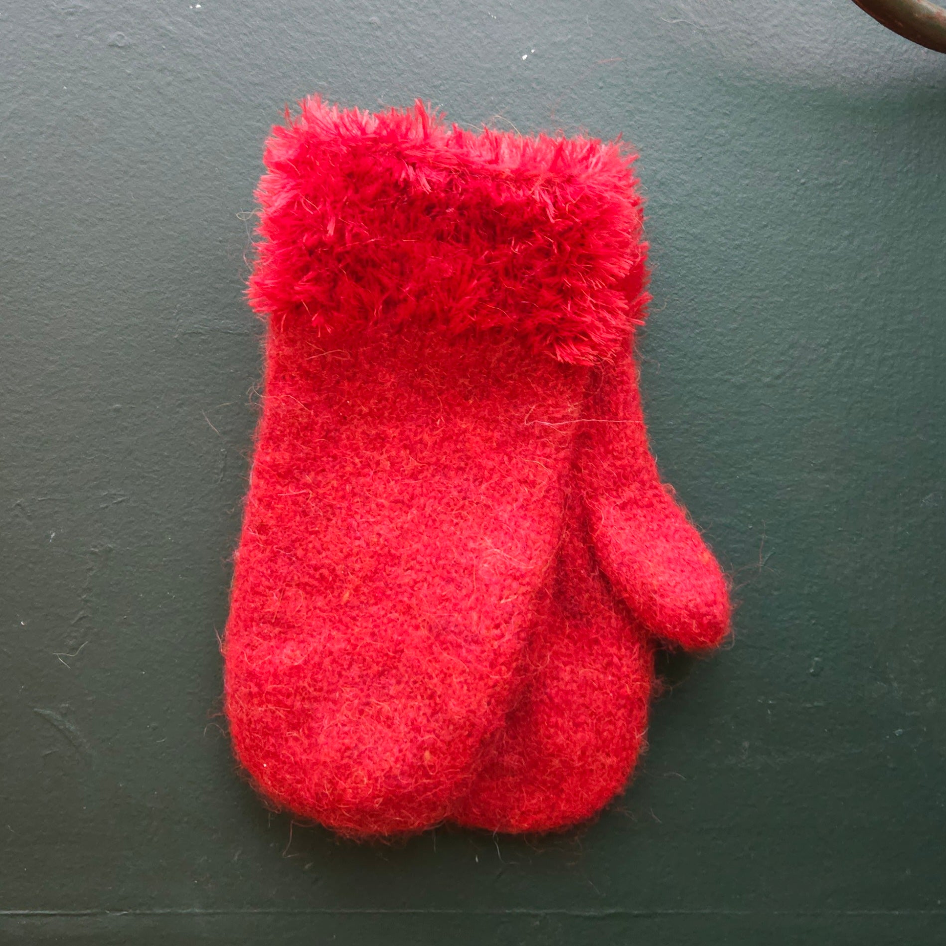 Red fluffy mitten on a green background