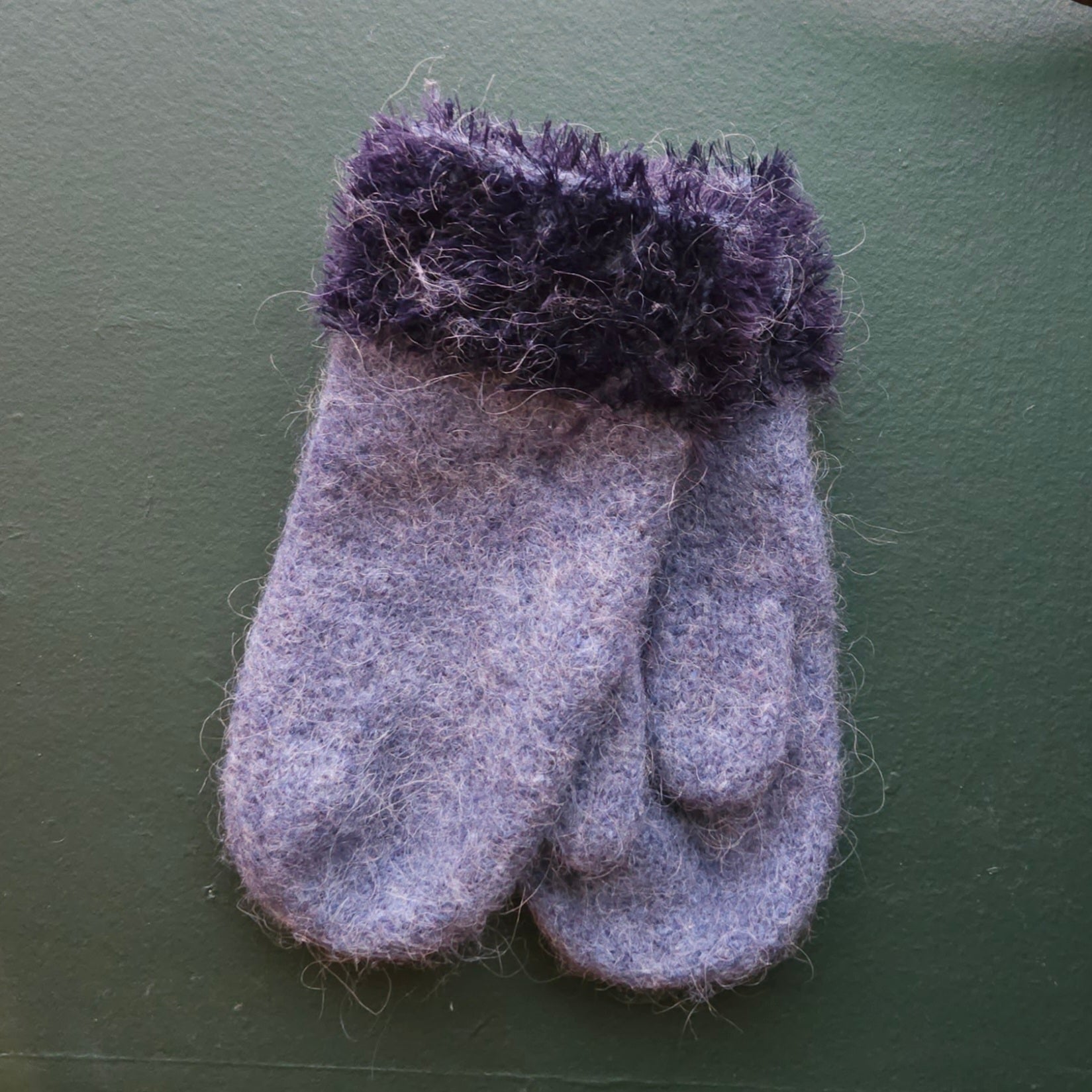 Blue fluffy mitten on a green background