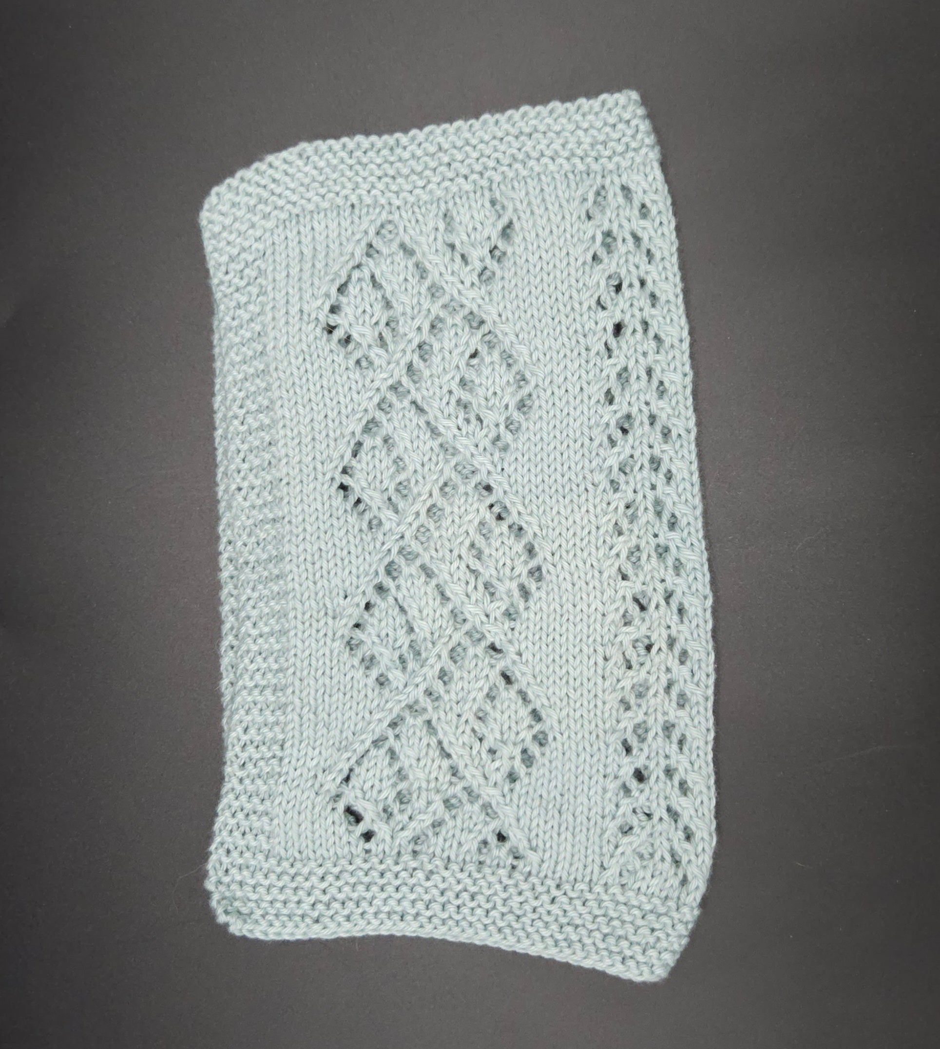 Knitted washcloth with a diamond pattern on a dark background