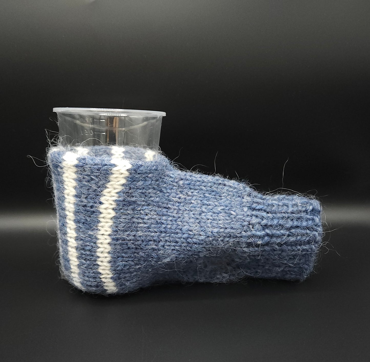 Blue knitted mitten for holding beer with a white stripe on a black background