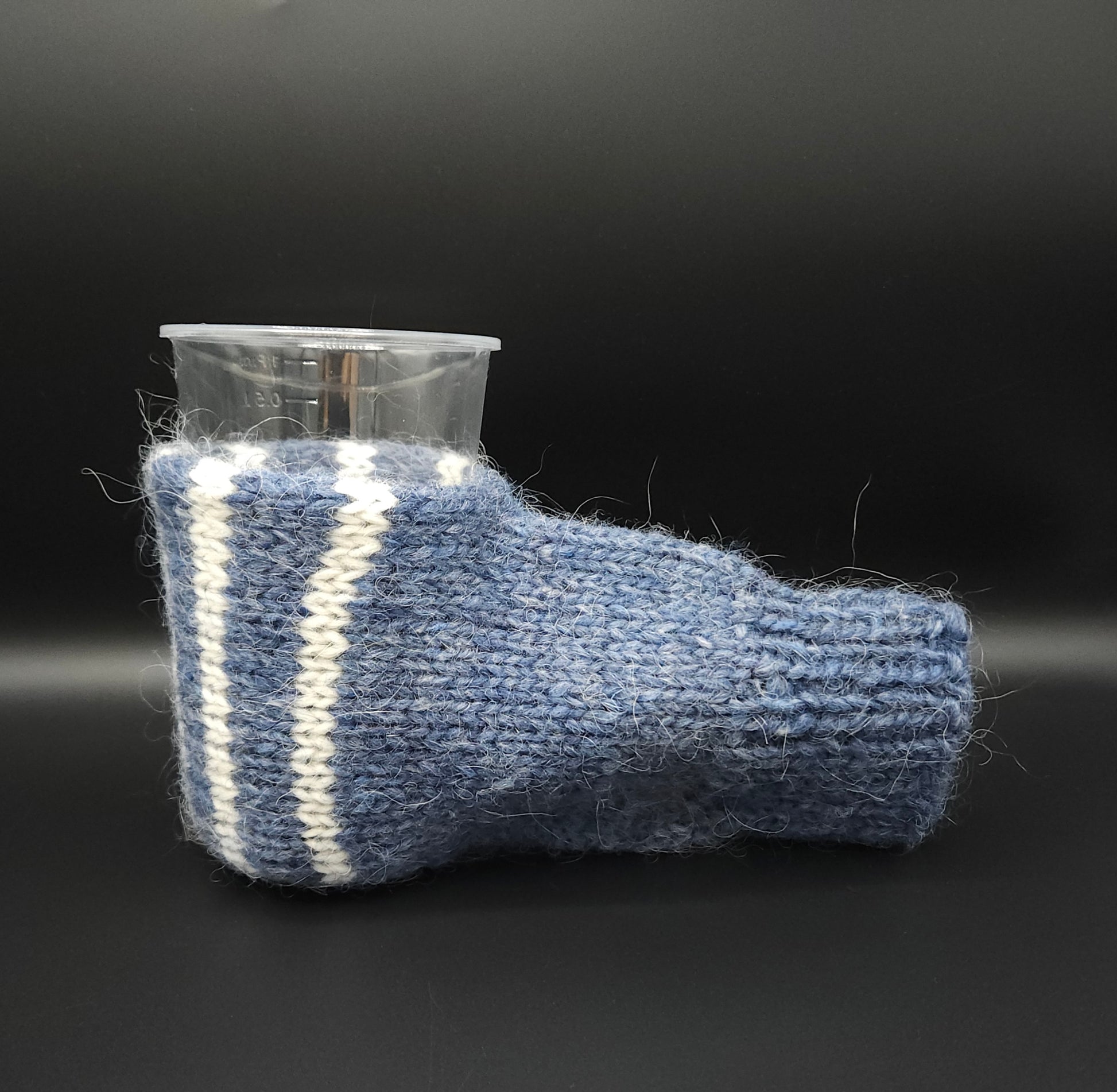 Blue knitted mitten for holding beer with a white stripe on a black background