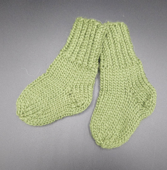 Pair of green knitted socks on a gray background