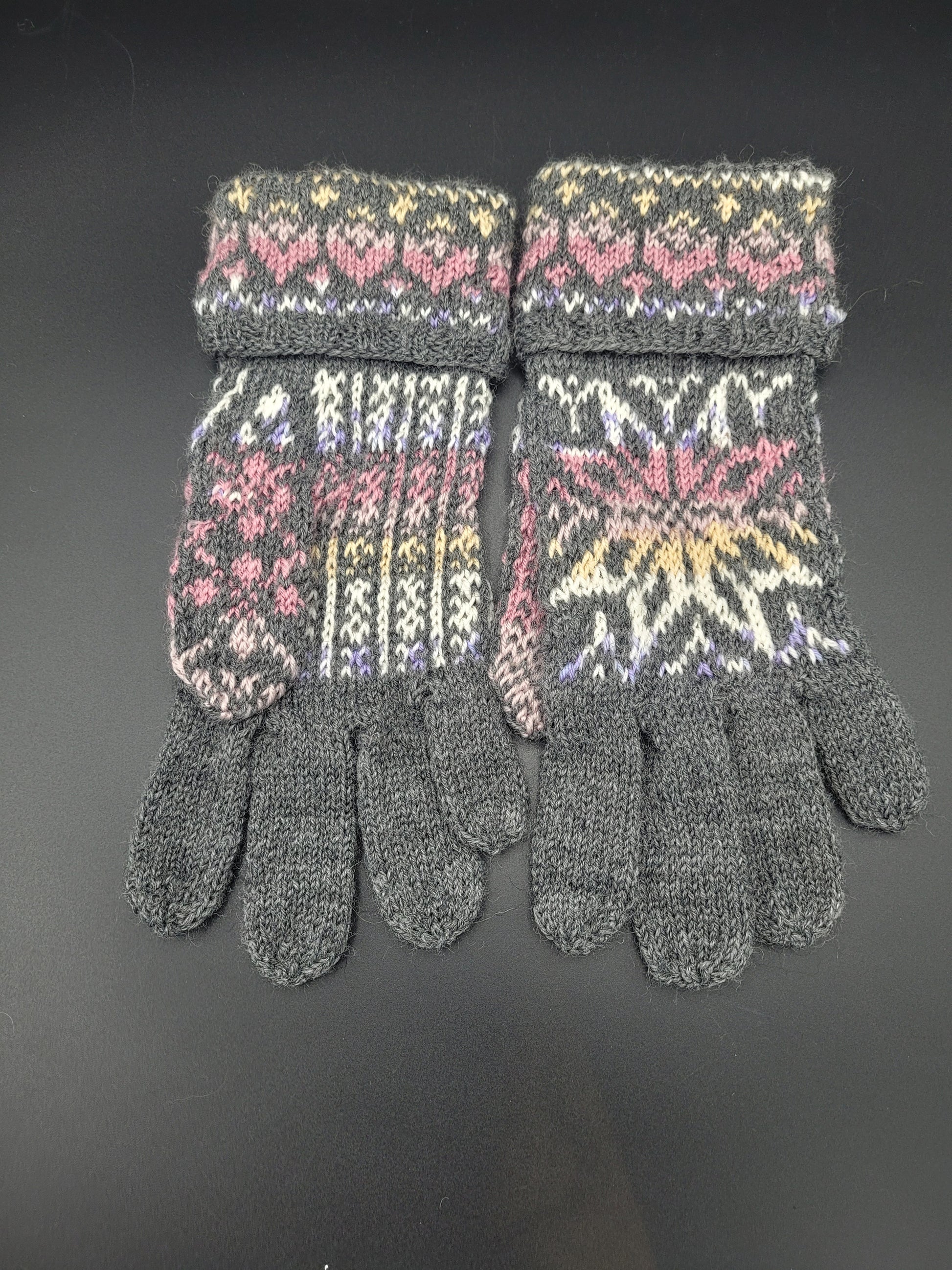 Pair of gloves with gray cuffs and colorful pattern on a black background
