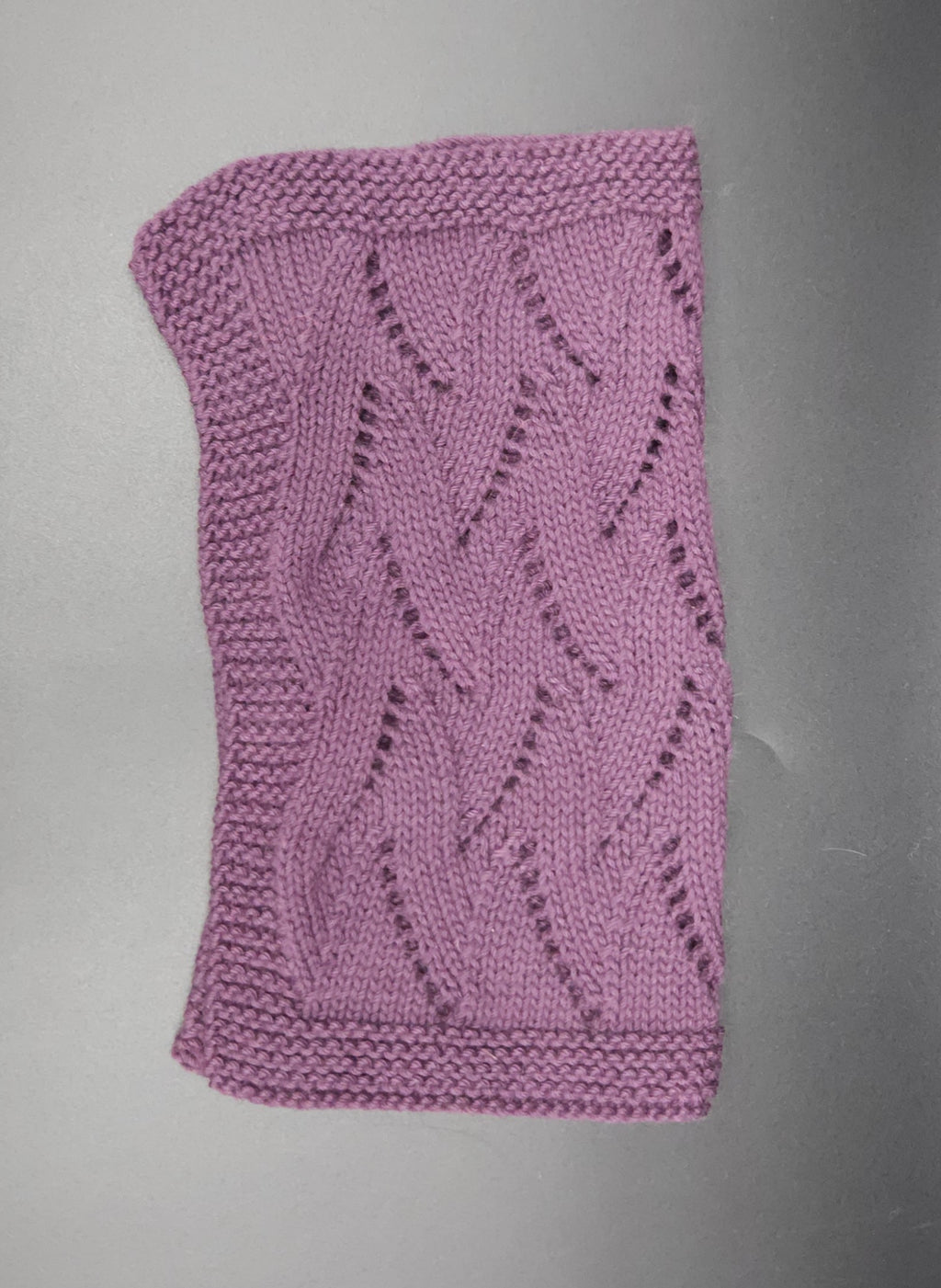Purple knitted washcloth with a pattern on a gray background