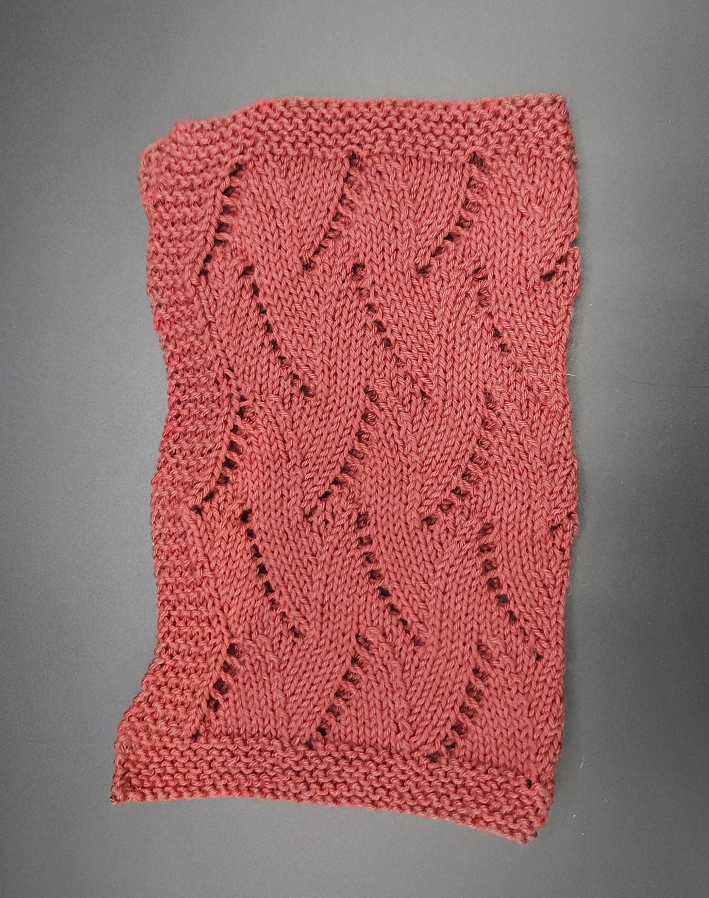 Knitted red washcloth with a textured pattern on a gray background