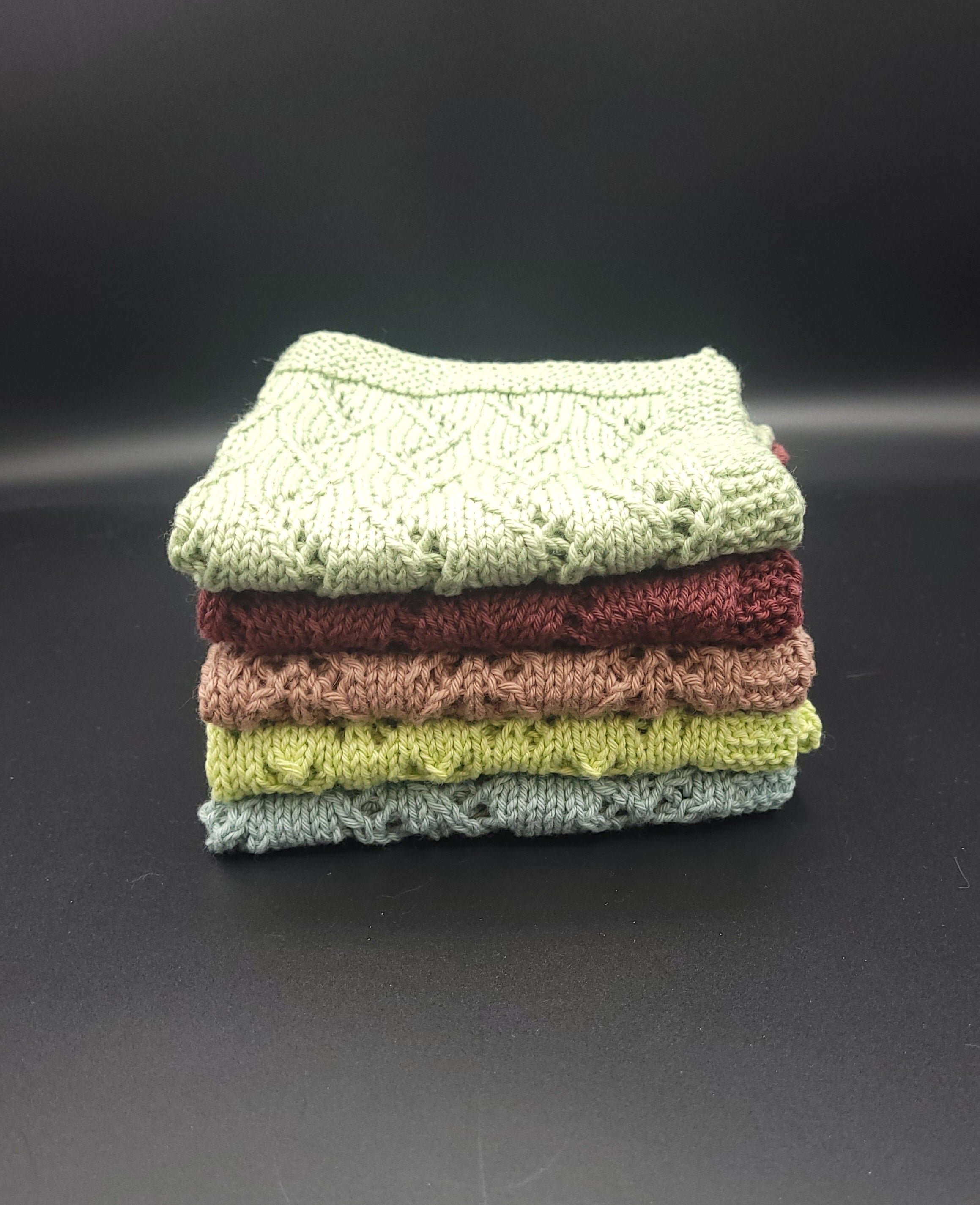 Stack of folded handknit washcloths on a black background