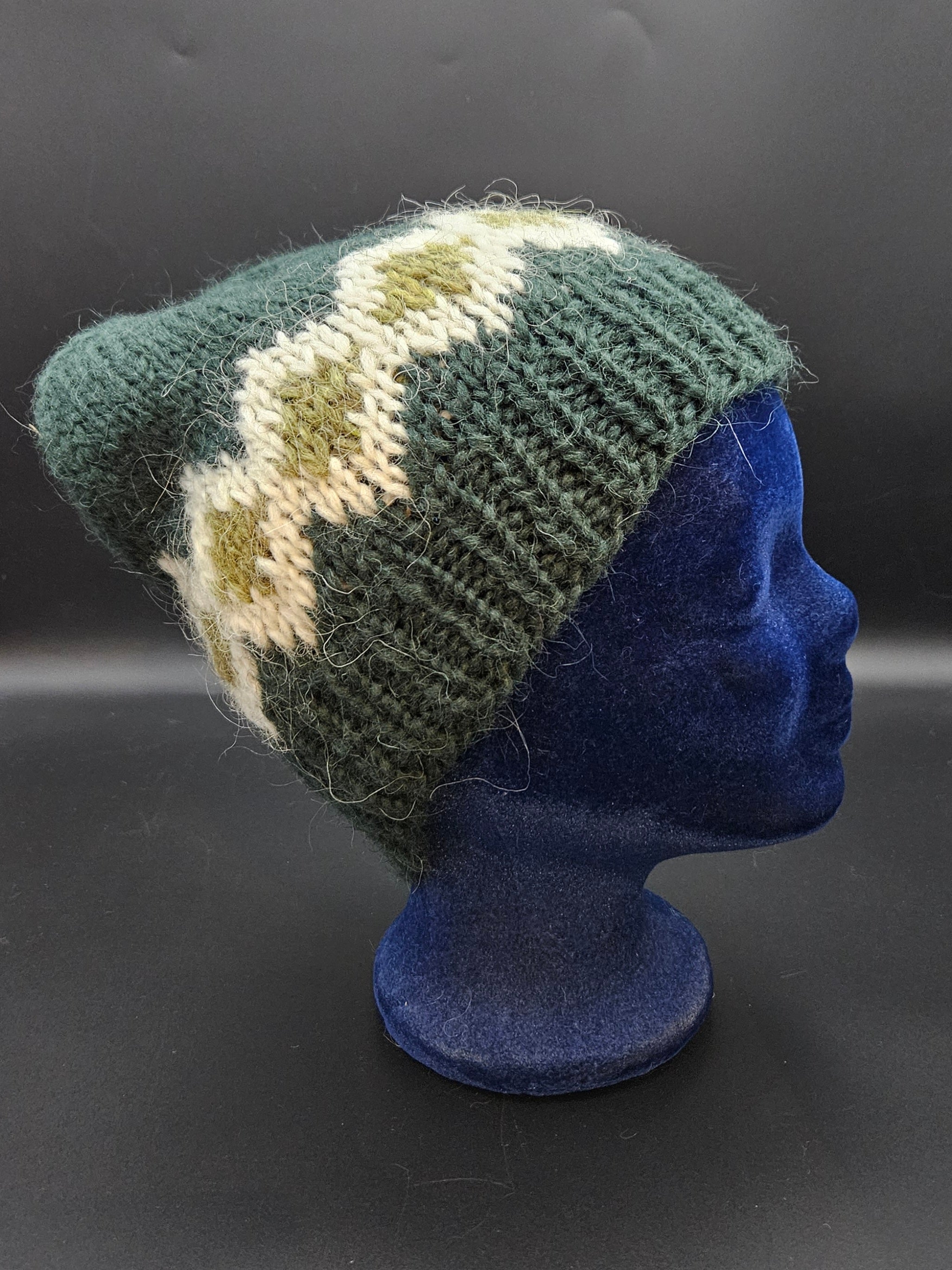 Knitted hat with a geometric pattern on a mannequin head against a dark background
