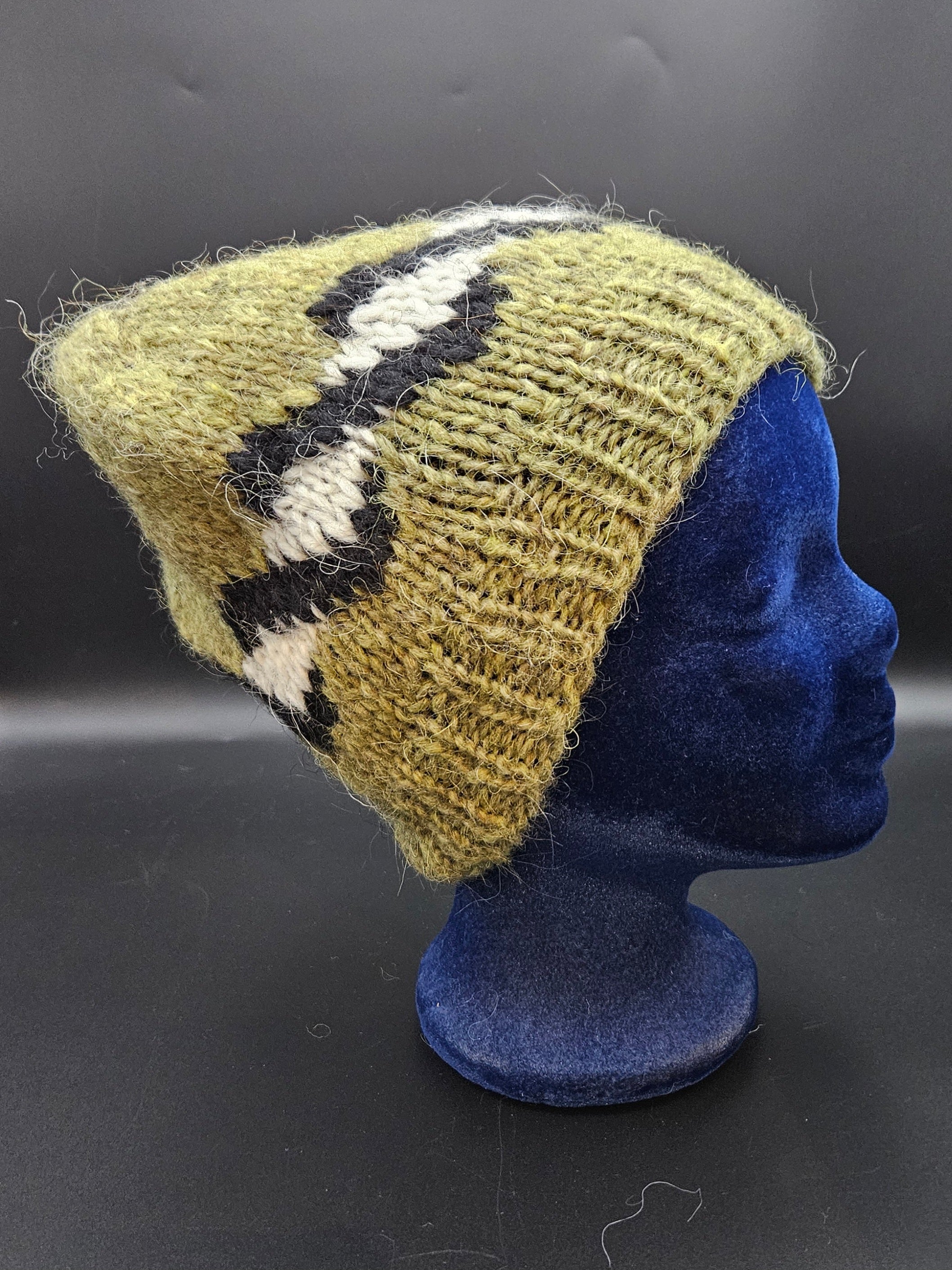 Knitted hat with geometric pattern on a blue mannequin head against a dark background