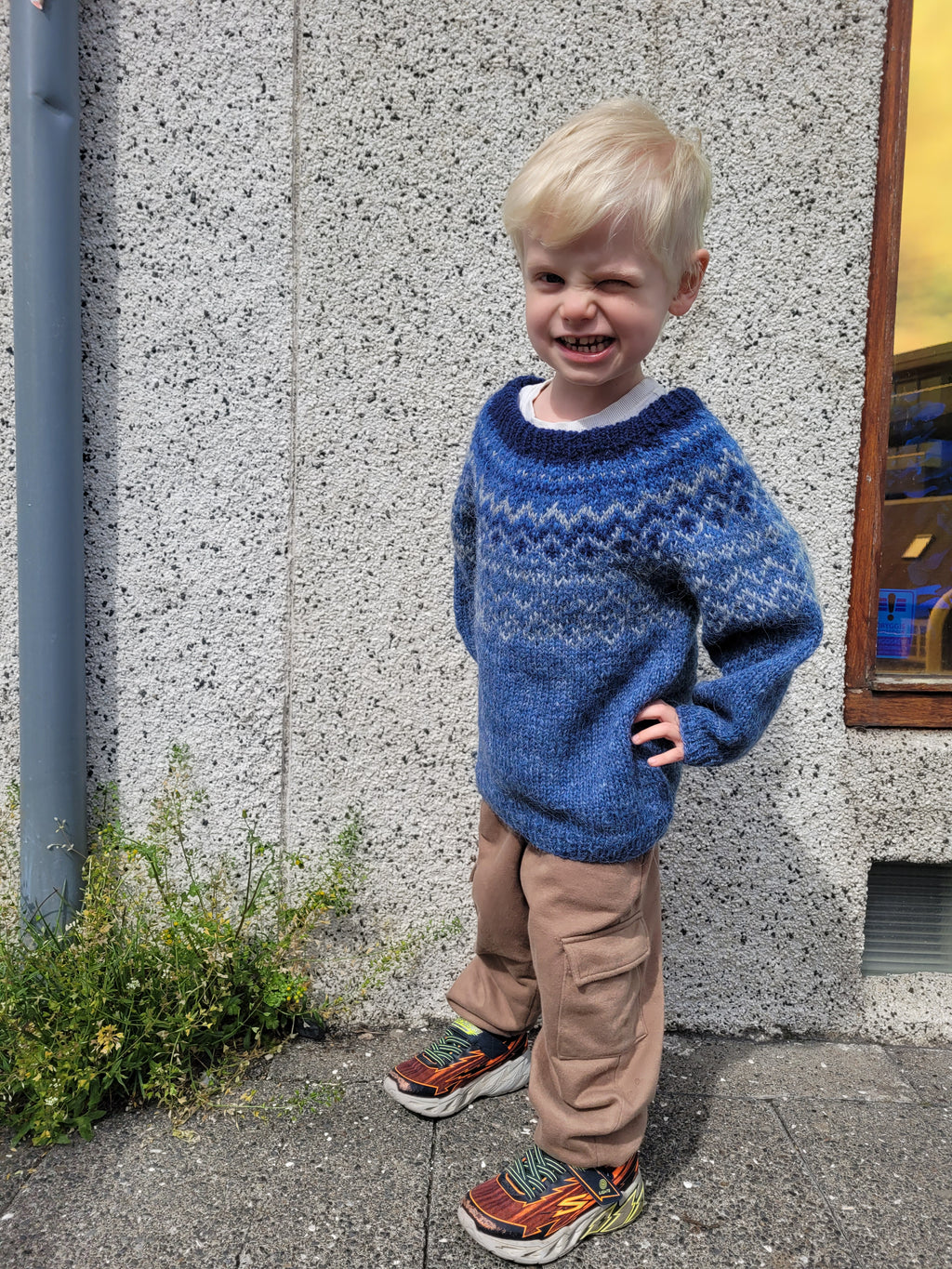 Child wearing a blue hand-knit Icelandic wool sweater featuring a traditional Nordic pattern