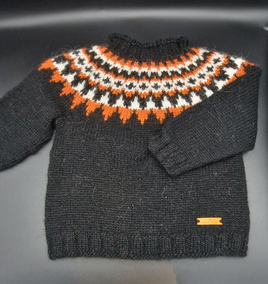 Black hand-knit Icelandic wool sweater featuring a traditional Nordic pattern in  white and orange colors on a black surface