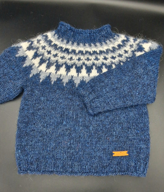 Blue hand-knit Icelandic wool sweater featuring a traditional Nordic pattern in  white and blue colors on a black surface