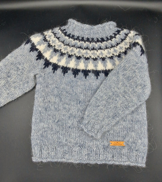 Hand-knit Icelandic wool sweater featuring a traditional Nordic pattern in gray, white, and dark blue colors on a black surface.
