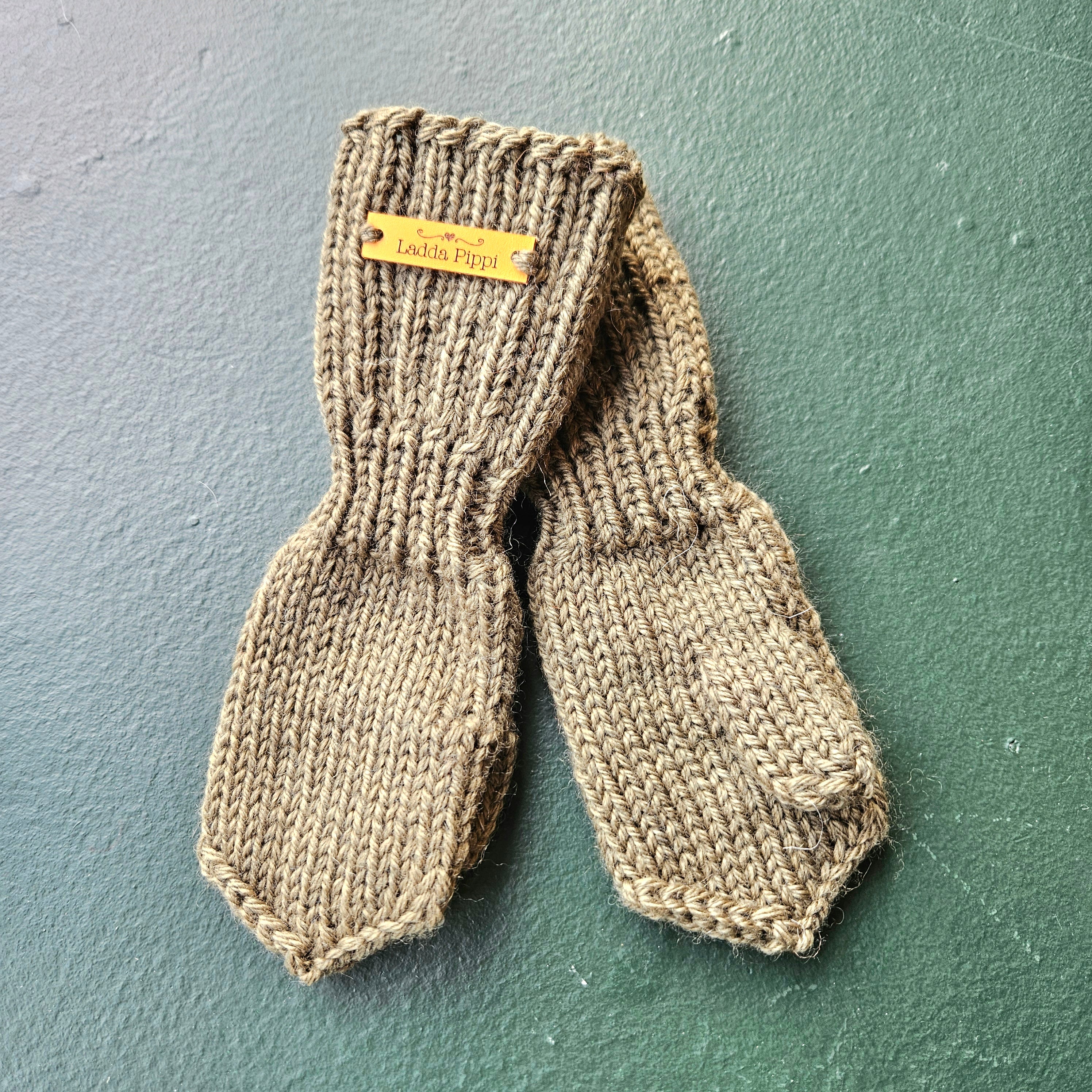 Pair of knitted mittens with a label on a solid background