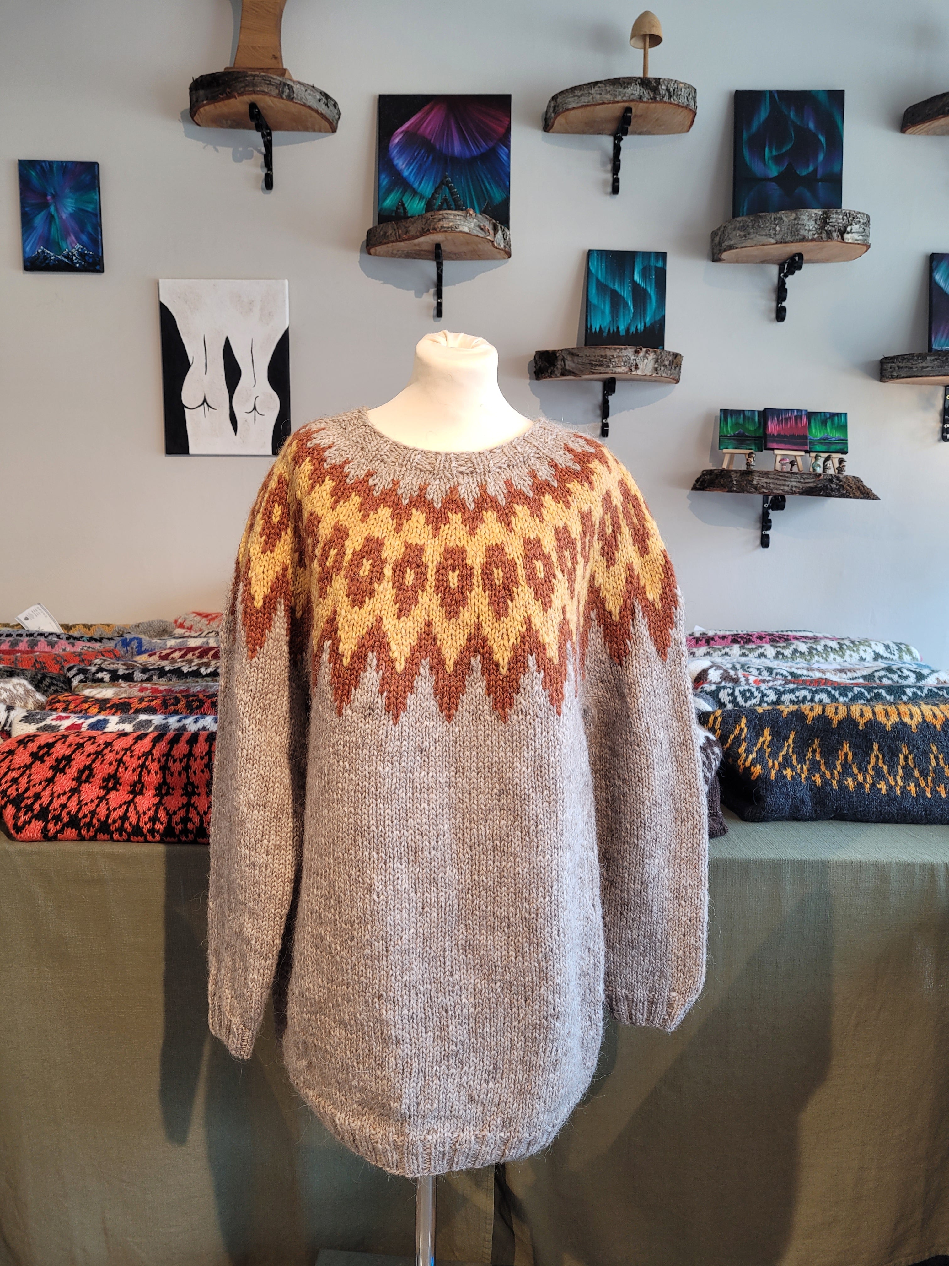 A mannequin in a hand-knit Icelandic wool sweater featuring a traditional Nordic pattern in brown, yellow, and beige colors.
