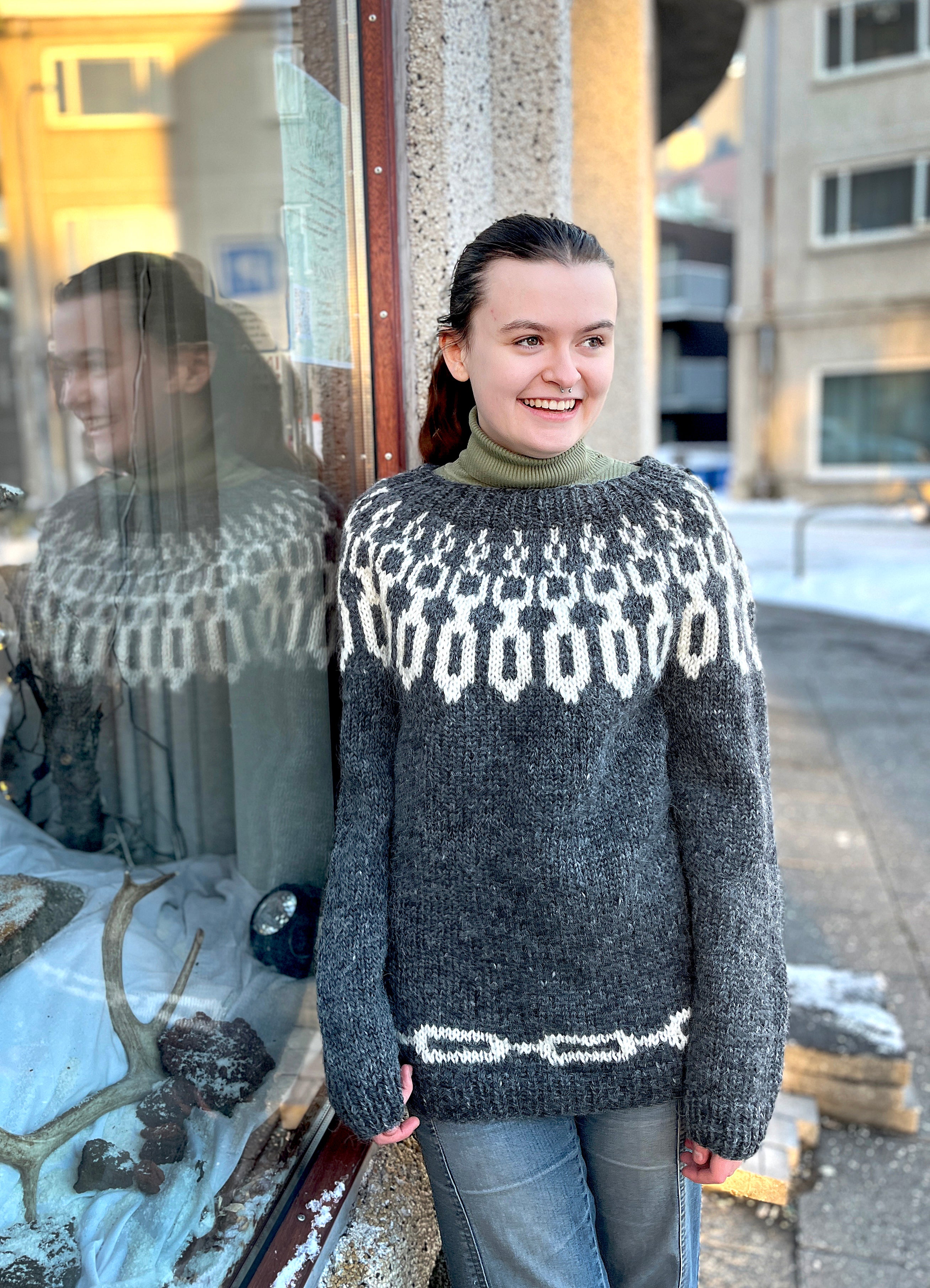 A woman in a hand knit Icelandic wool sweater featuring a traditional Nordic pattern that resembles chains