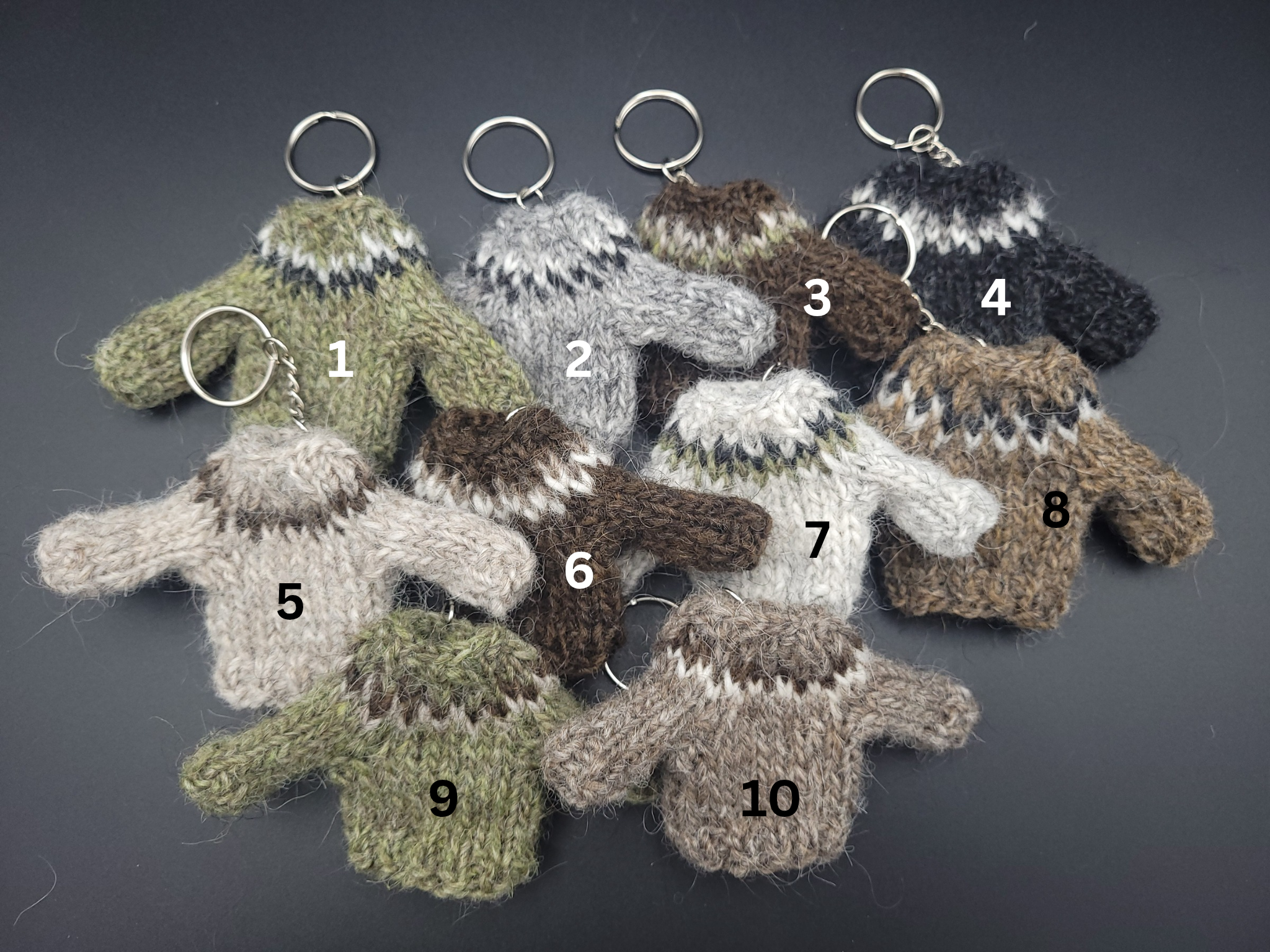 Collection of knitted sweater keychains in various colors on a dark background