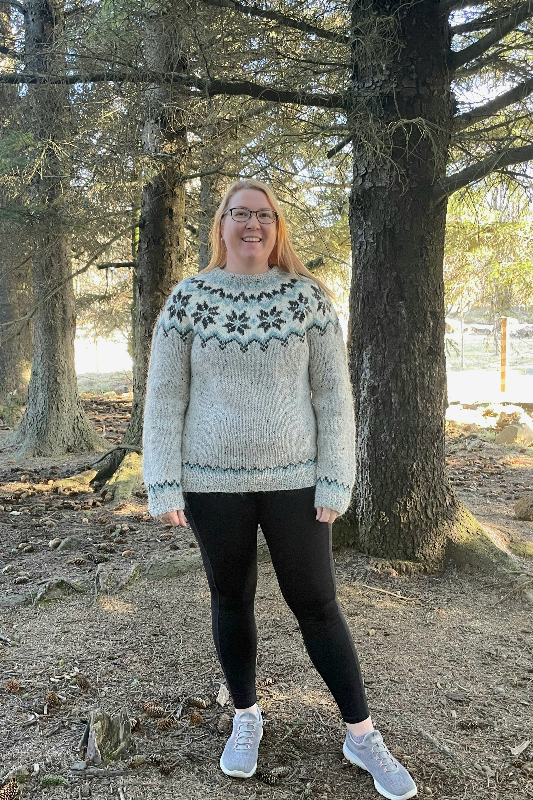 Person wearing a patterned sweater standing in a forest