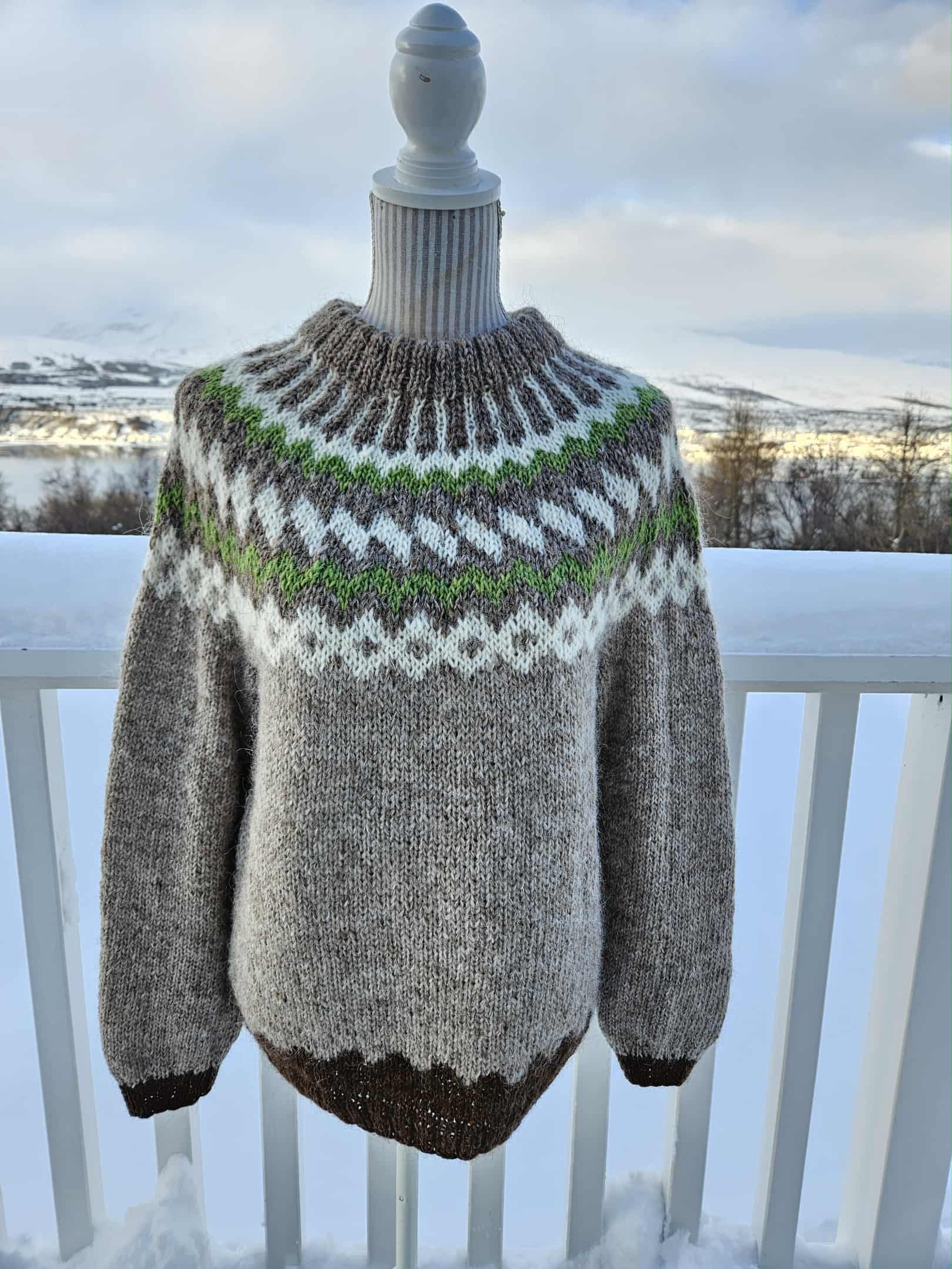 Knitted sweater with a pattern on a mannequin against a snowy landscape.
