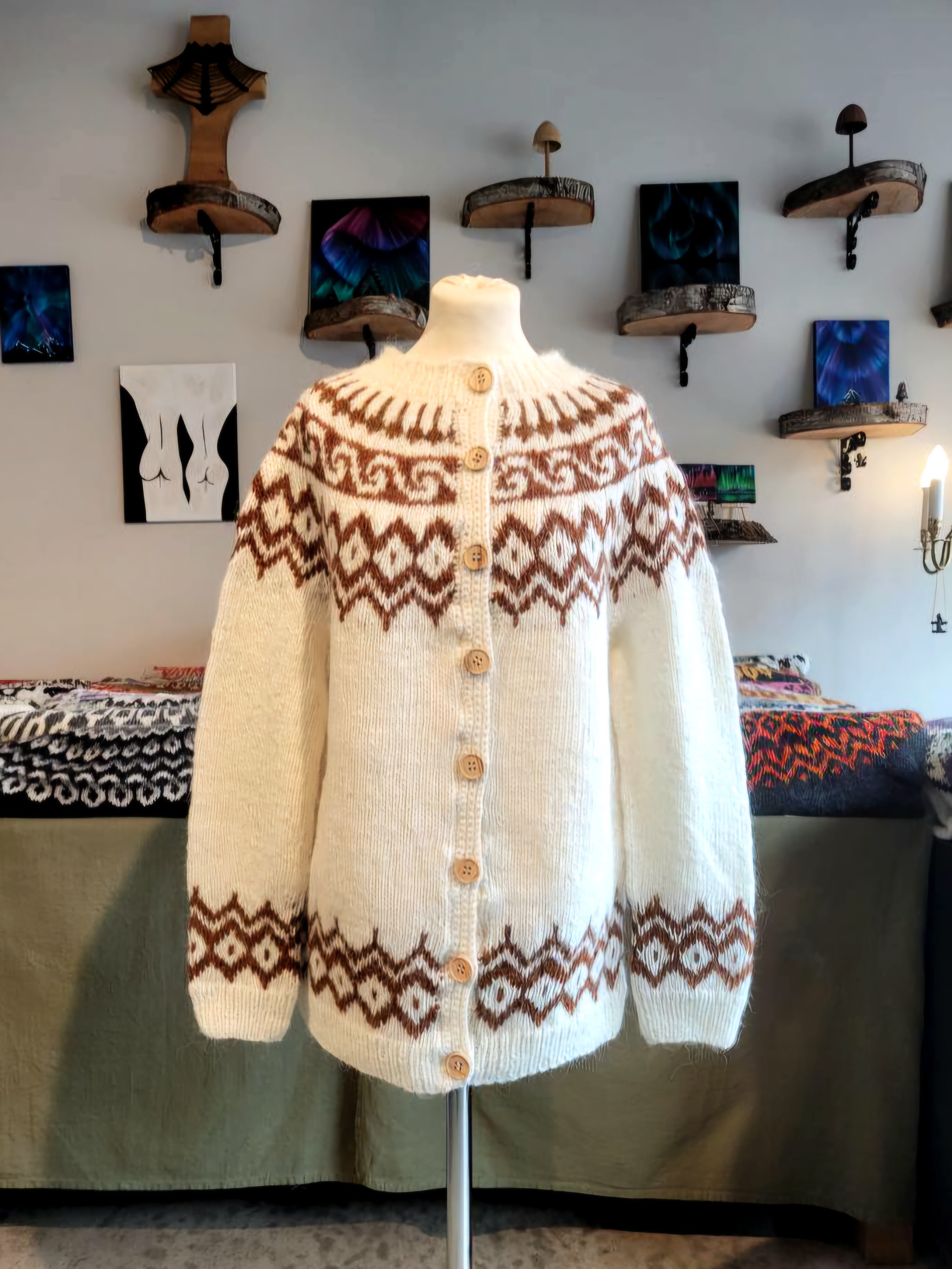 White knitted cardigan with brown nordic patterns on a mannequin in a store setting