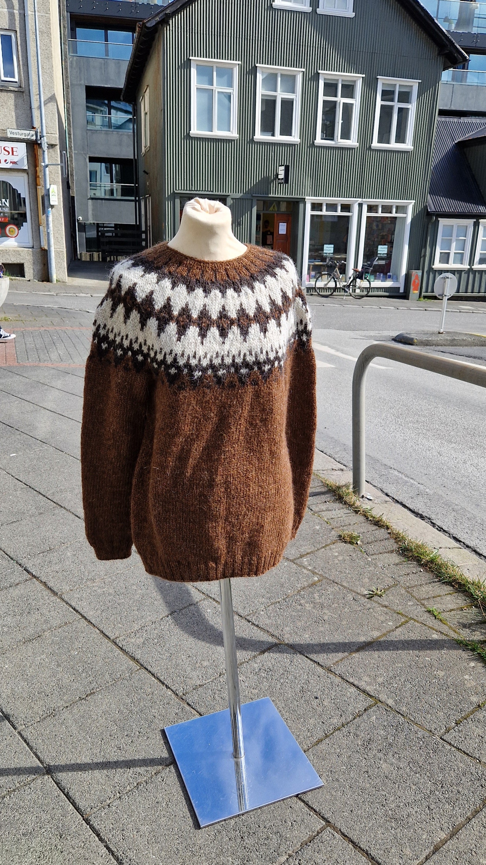 A brown and white Icelandic wool sweater displayed on a mannequin outdoors.