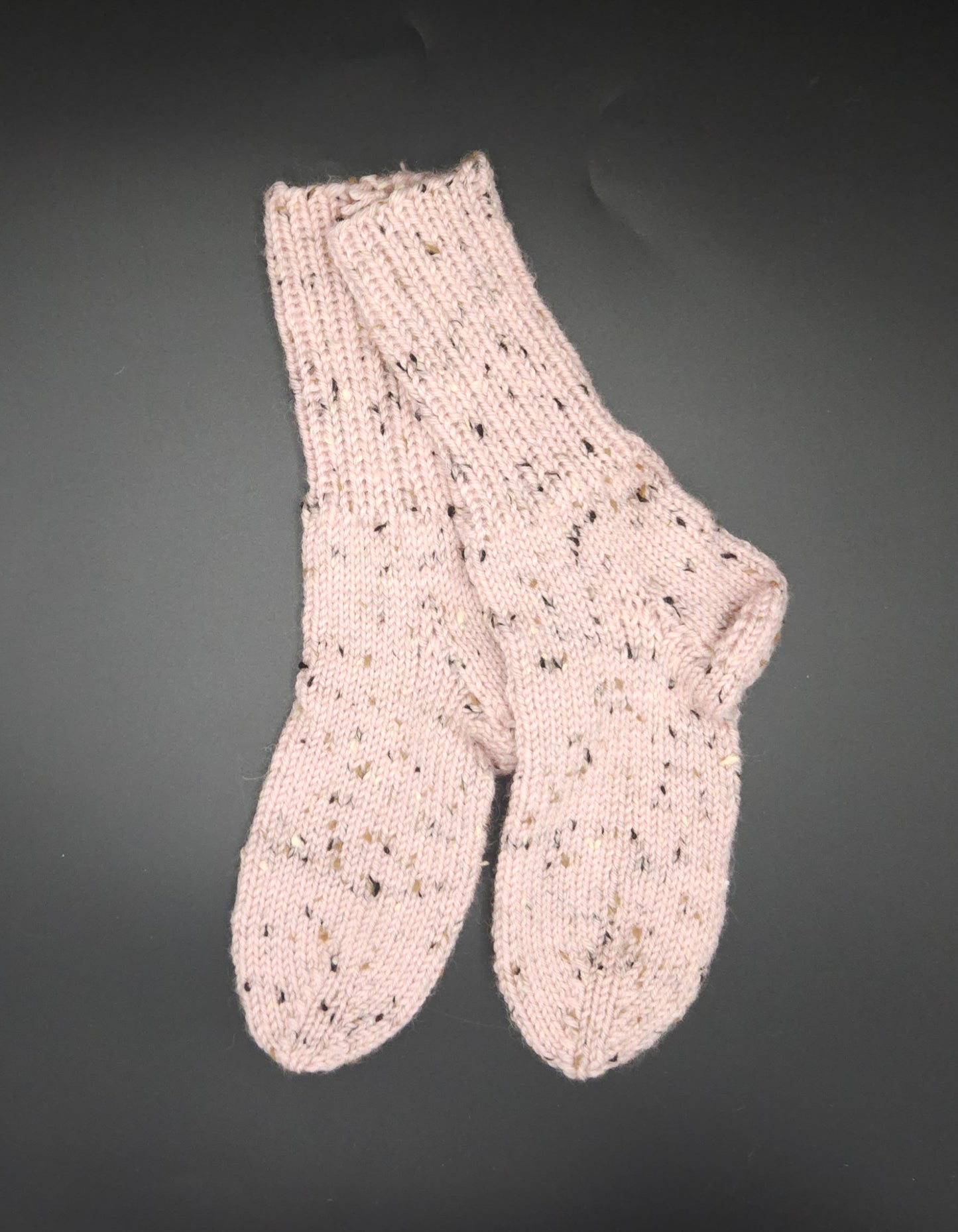 Pair of pink knitted socks on a dark background