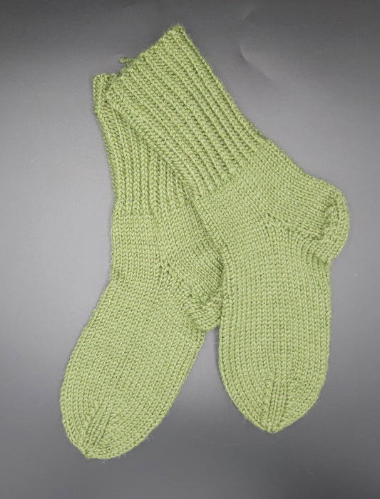 Pair of green knitted socks on a gray background