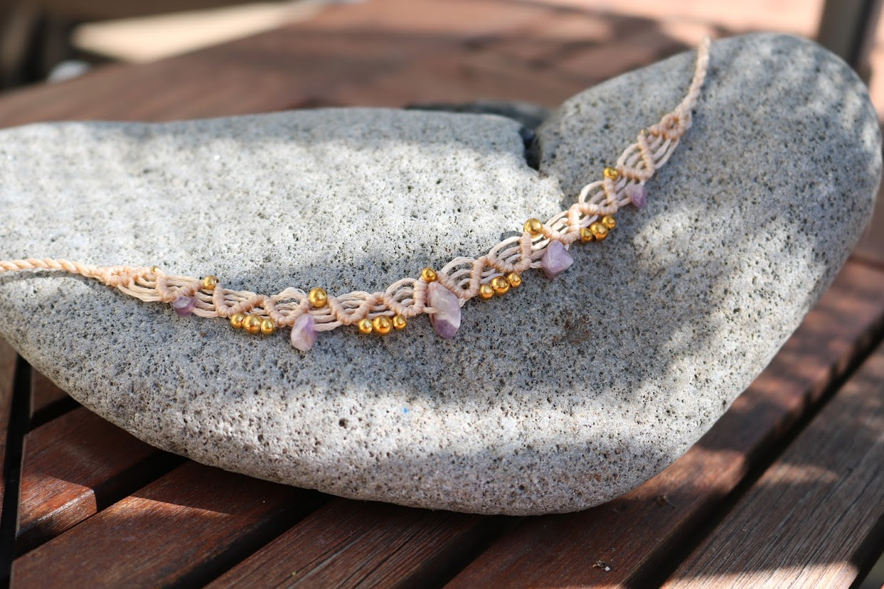 Necklace with pink amethyst stones and gold accents on a stone surface