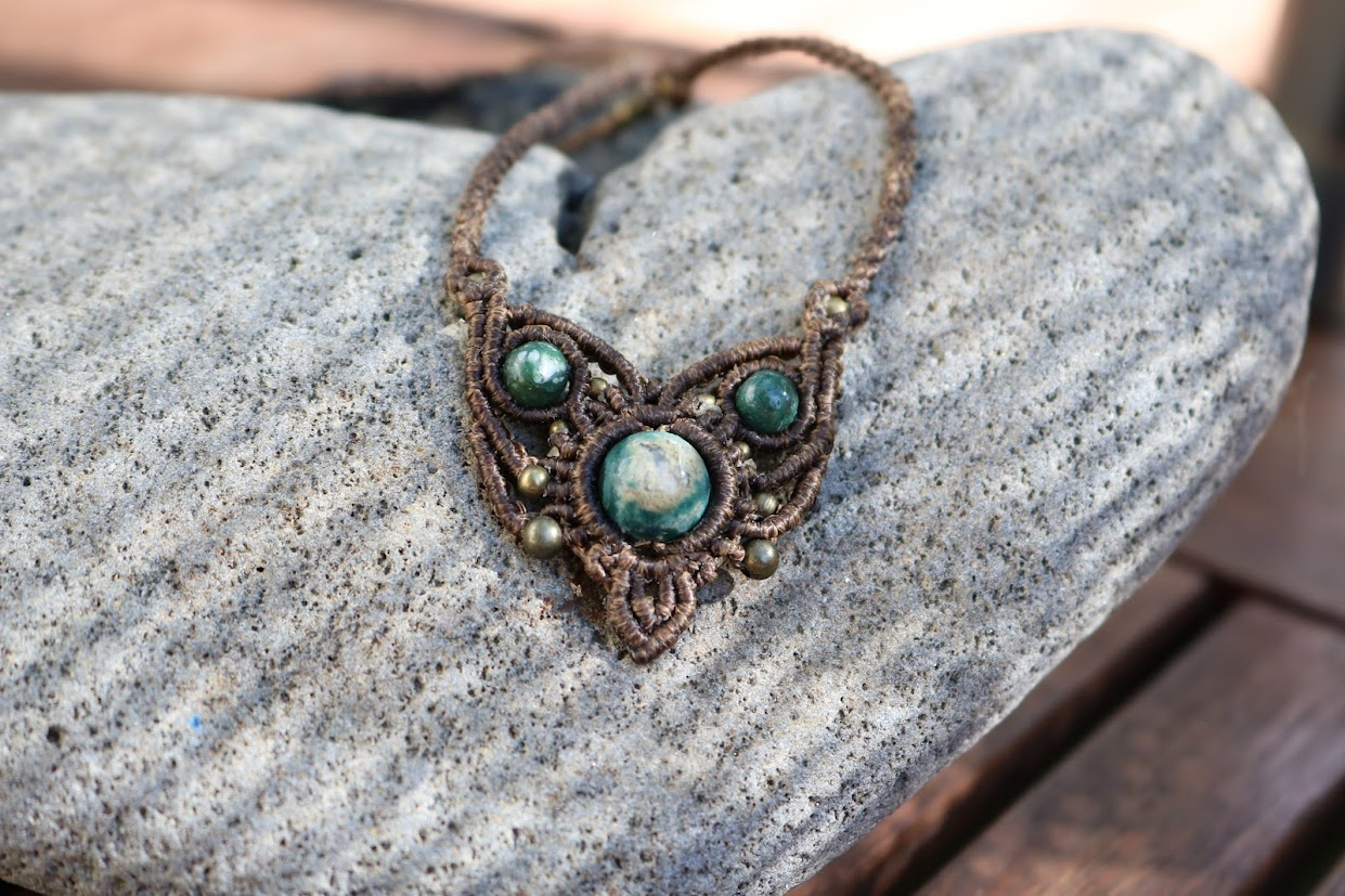 Necklace with green stones on a textured stone surface