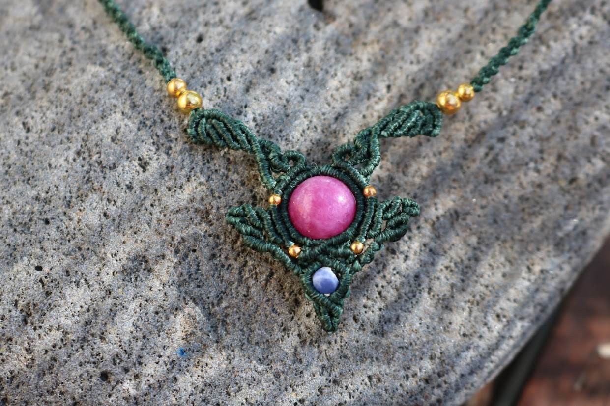Necklace with green lacework and pink and purple stones on a stone surface