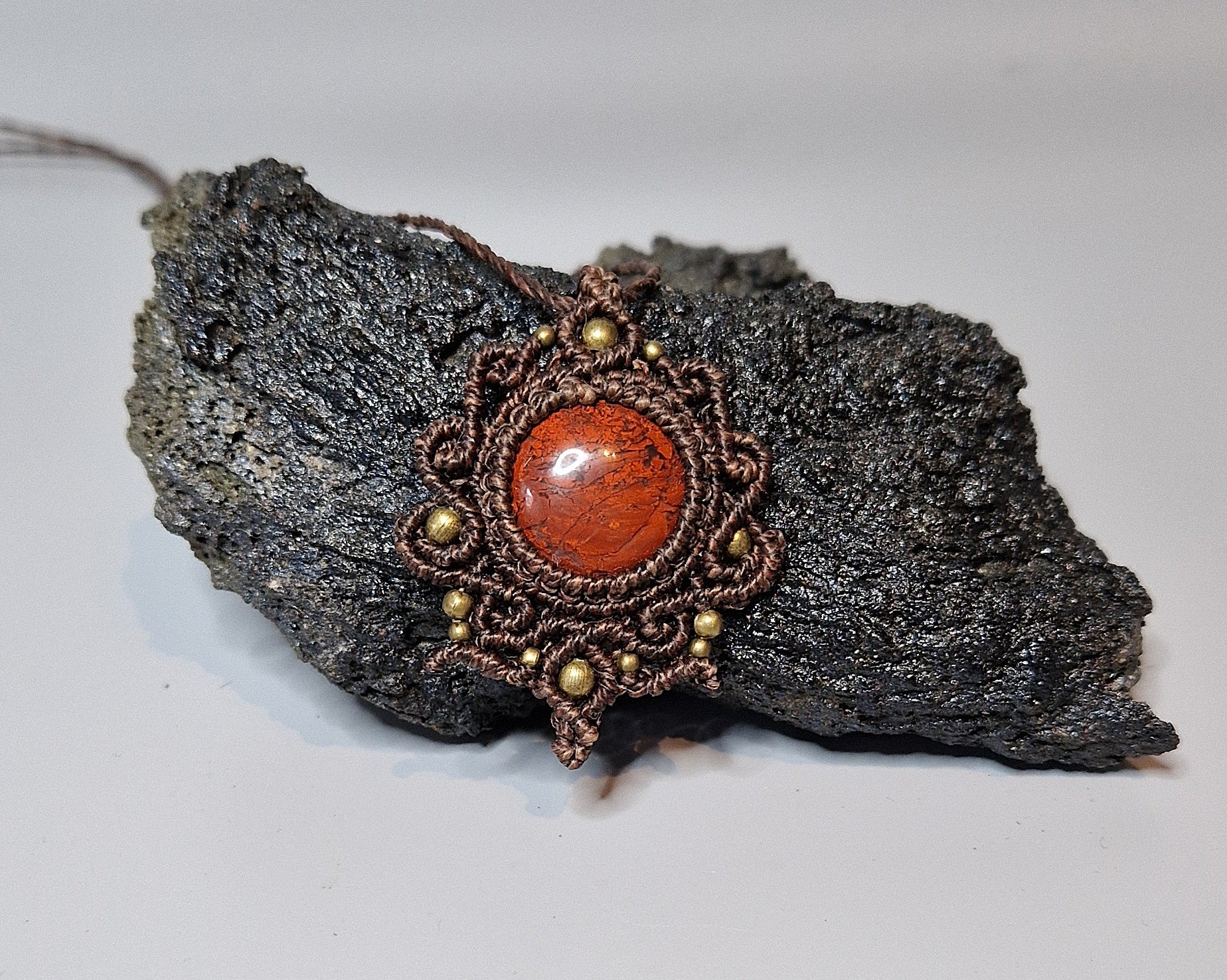 Jewelry with a red stone and gold accents on a textured rock surface