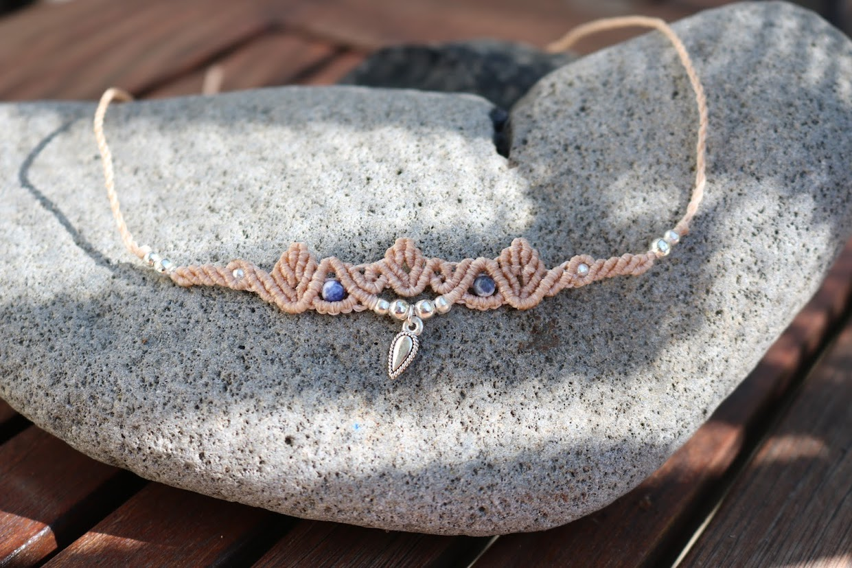 Necklace with sodalite stone and charm on a stone surface