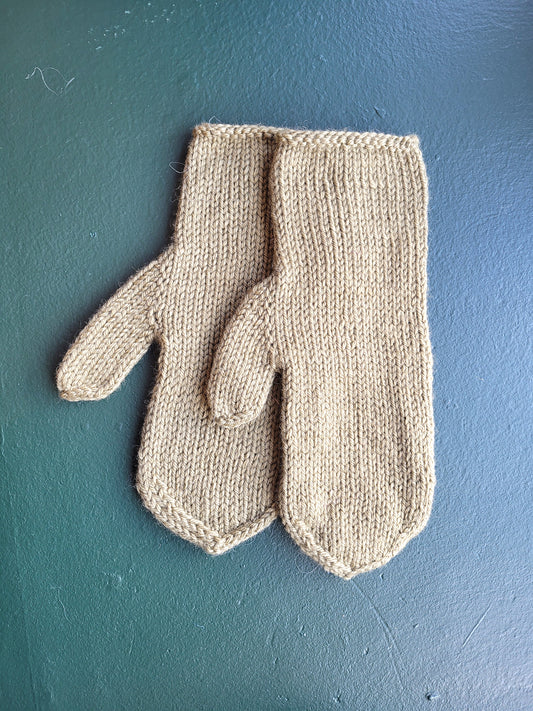 Pair of green knitted mittens on a blue surface