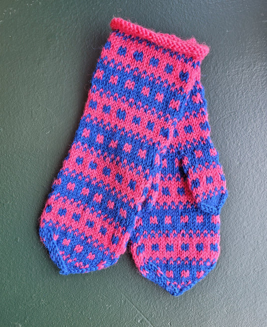 Knitted pink and blue mittens on a dark green background