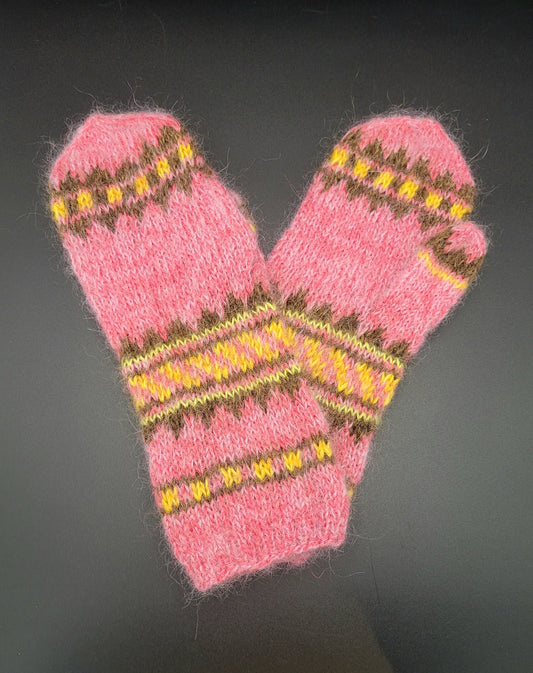 Pair of pink knitted mittens with yellow and brown patterns on a dark background