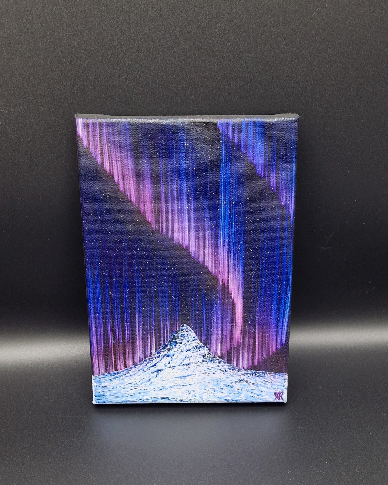 Painting of a landscape with northern lights on a black background.