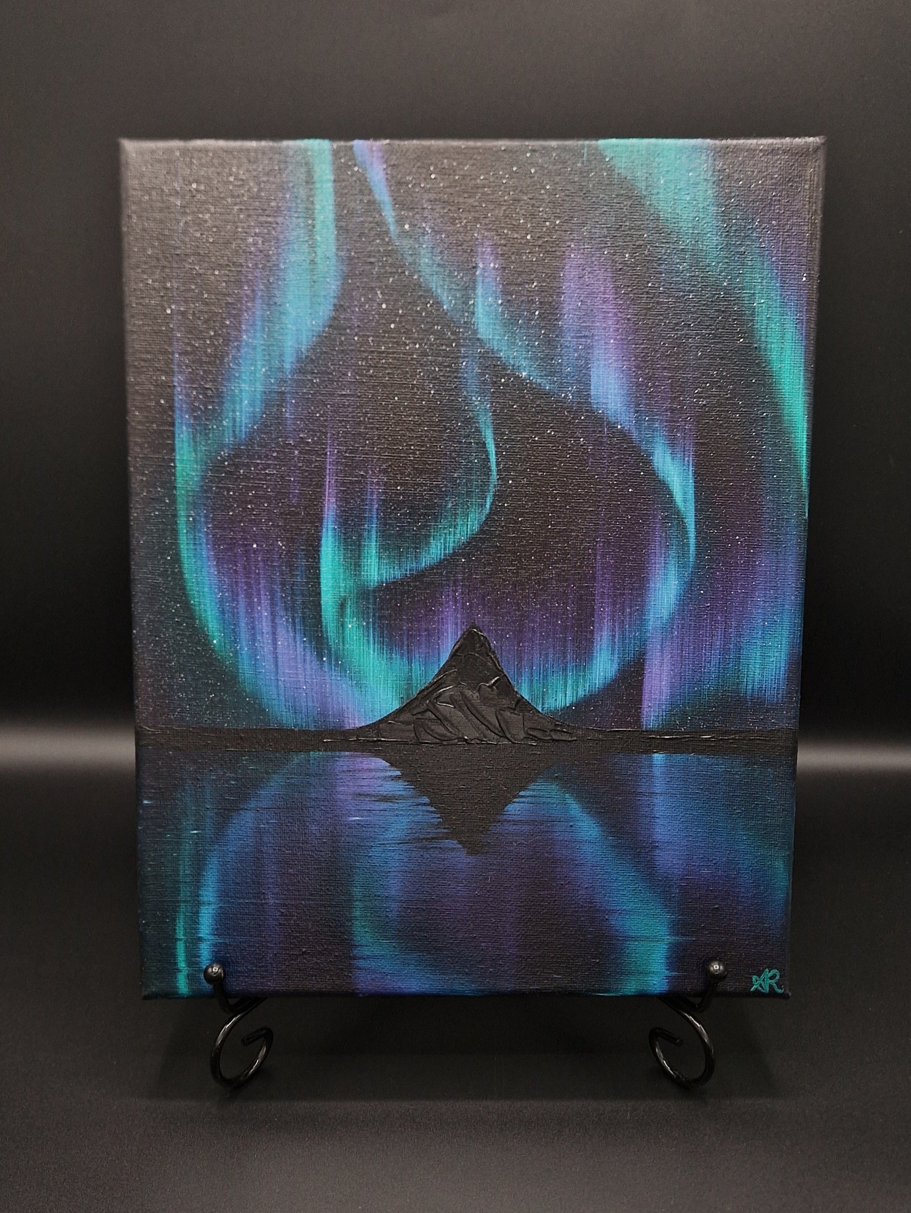 Painting with northern lights and black mountains.