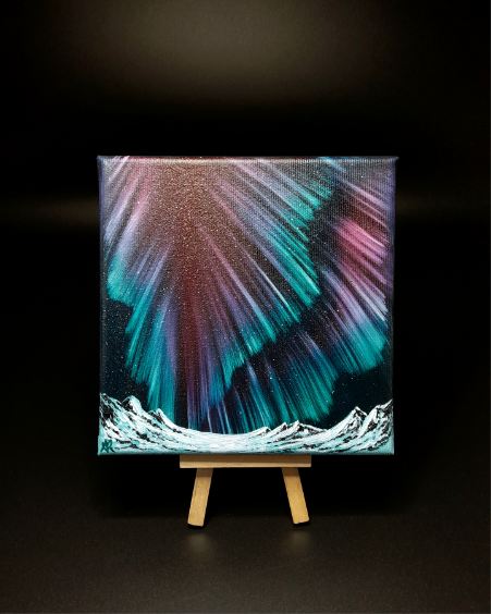 Northern lights artwork on a canvas with a wooden easel against a dark background