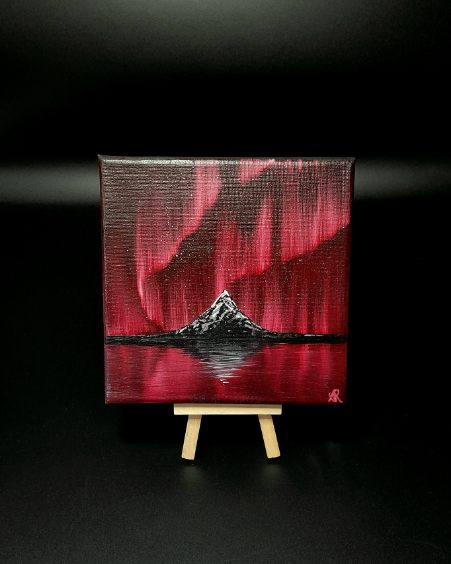 Painting of a mountain with red and black northern lights design on a dark background